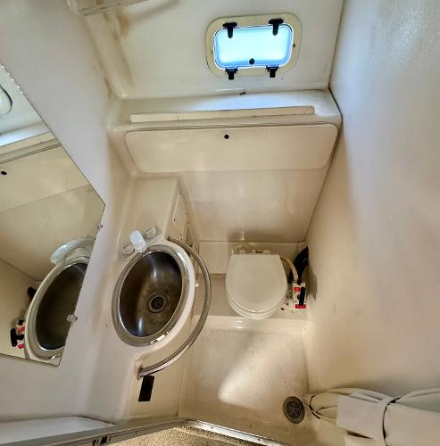 1997 Maxum 3200 SCR boat bathroom with sink, toilet, and porthole window.