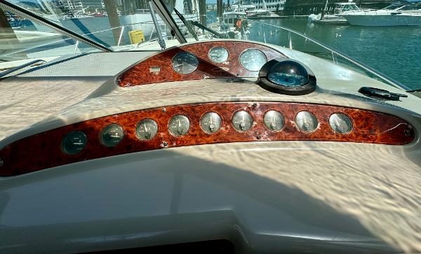 1997 Maxum 3200 SCR boat dashboard with wood paneling and gauges, docked at marina.