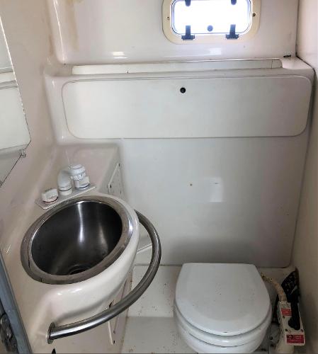 1997 Maxum 3200 SCR boat bathroom with sink, toilet, and small window.