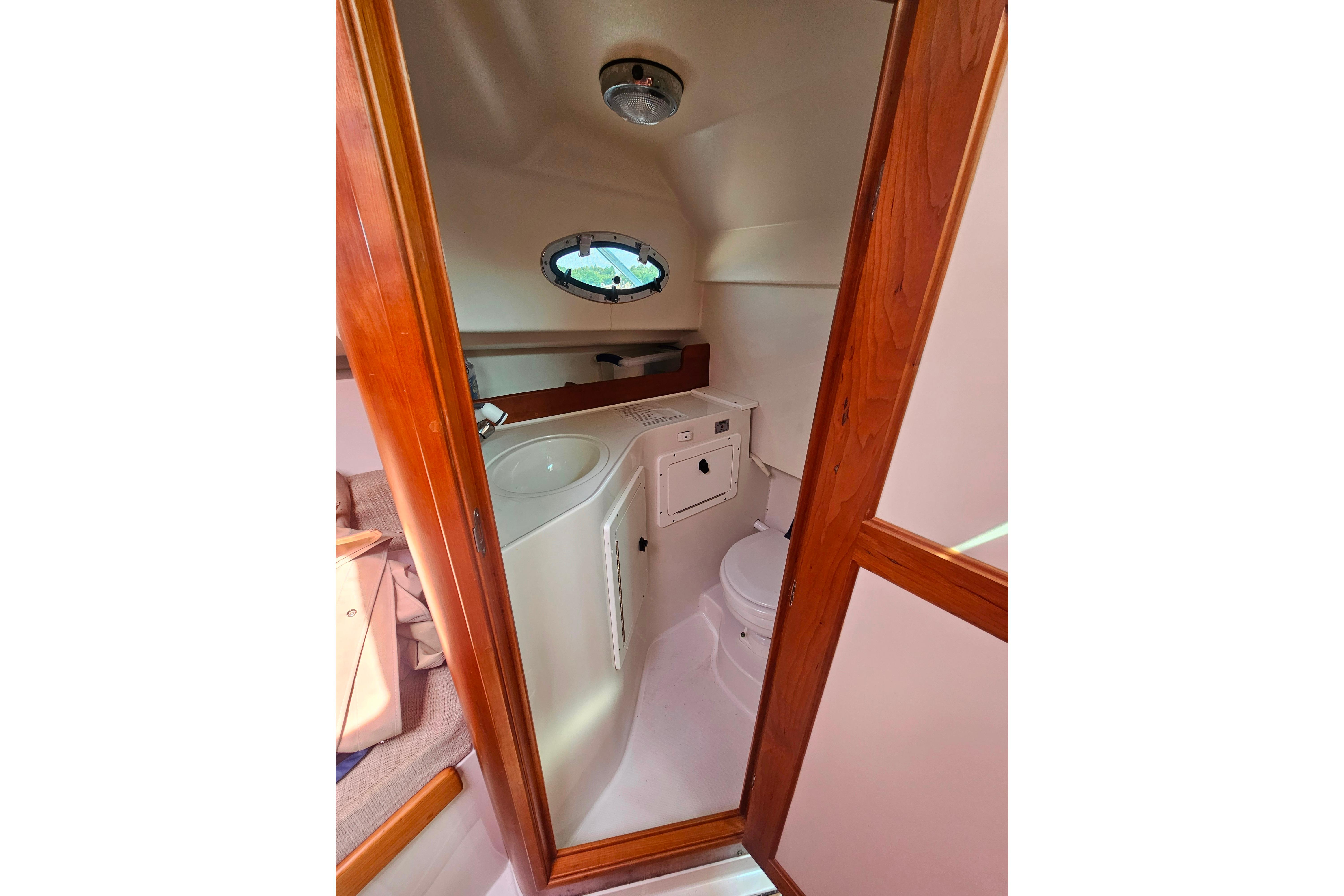 2006 Back Cove 26 boat interior with compact bathroom and wooden door.