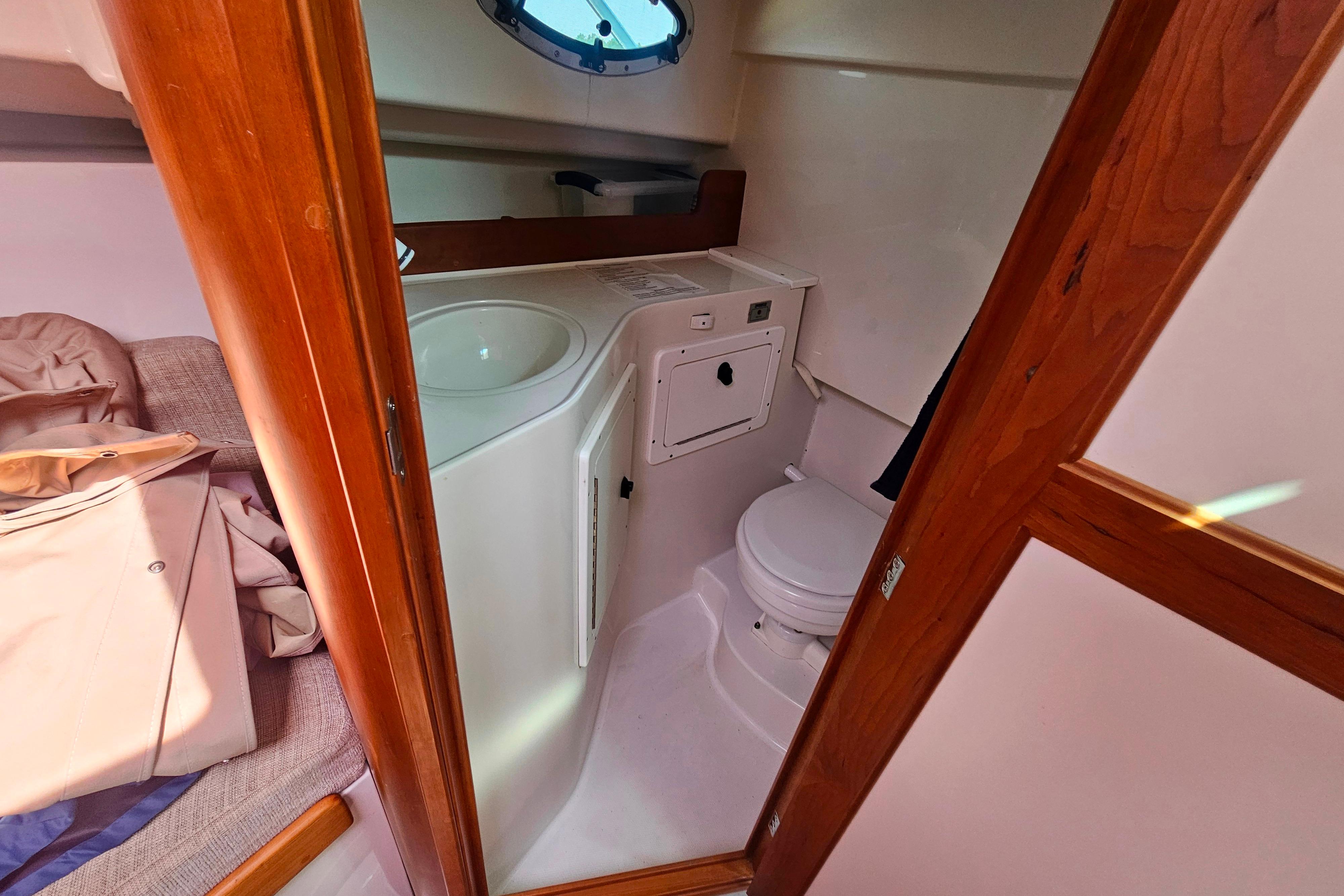 2006 Back Cove 26 boat interior with compact bathroom and wooden accents.