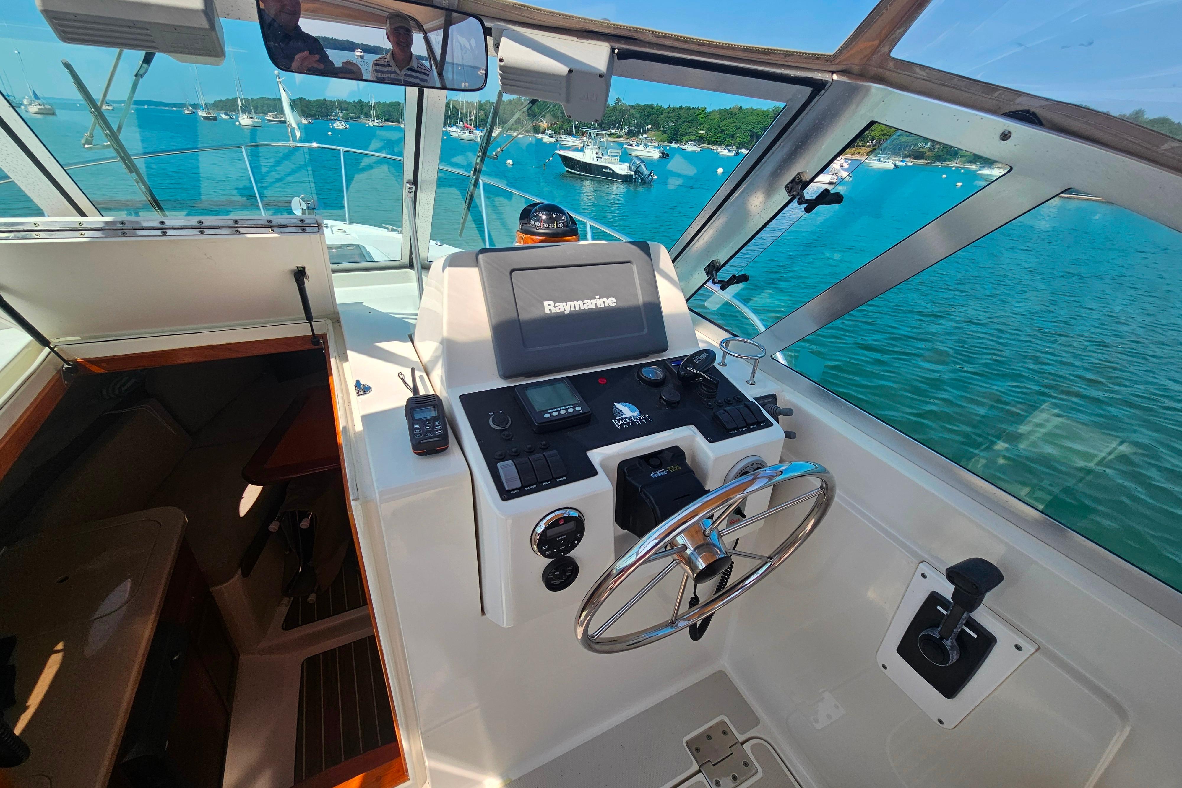 2006 Back Cove 26 boat cockpit with steering wheel and navigation equipment, overlooking a serene marina.