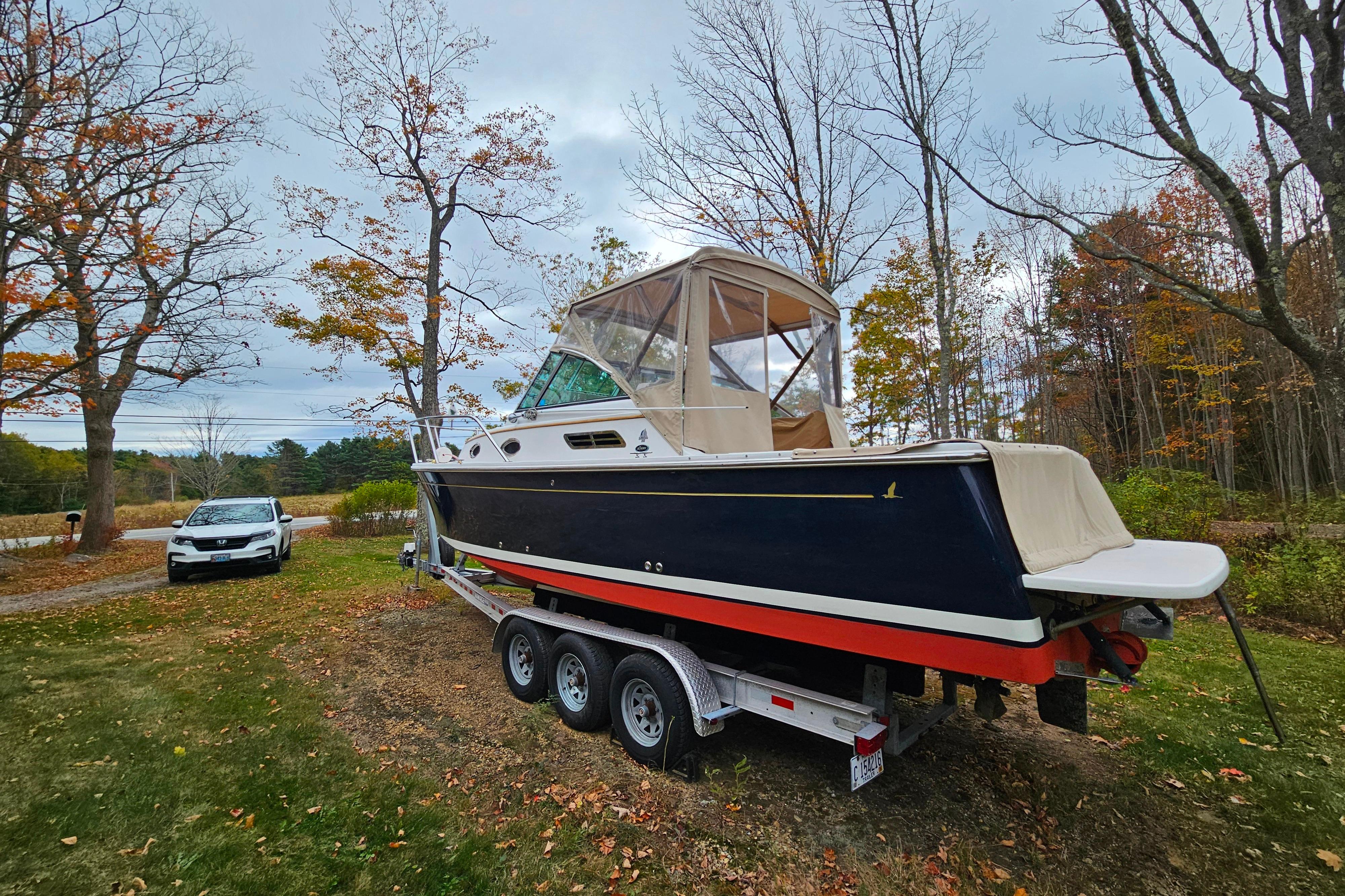 2006 Back Cove 26 boat on trailer, surrounded by autumn trees and parked car.