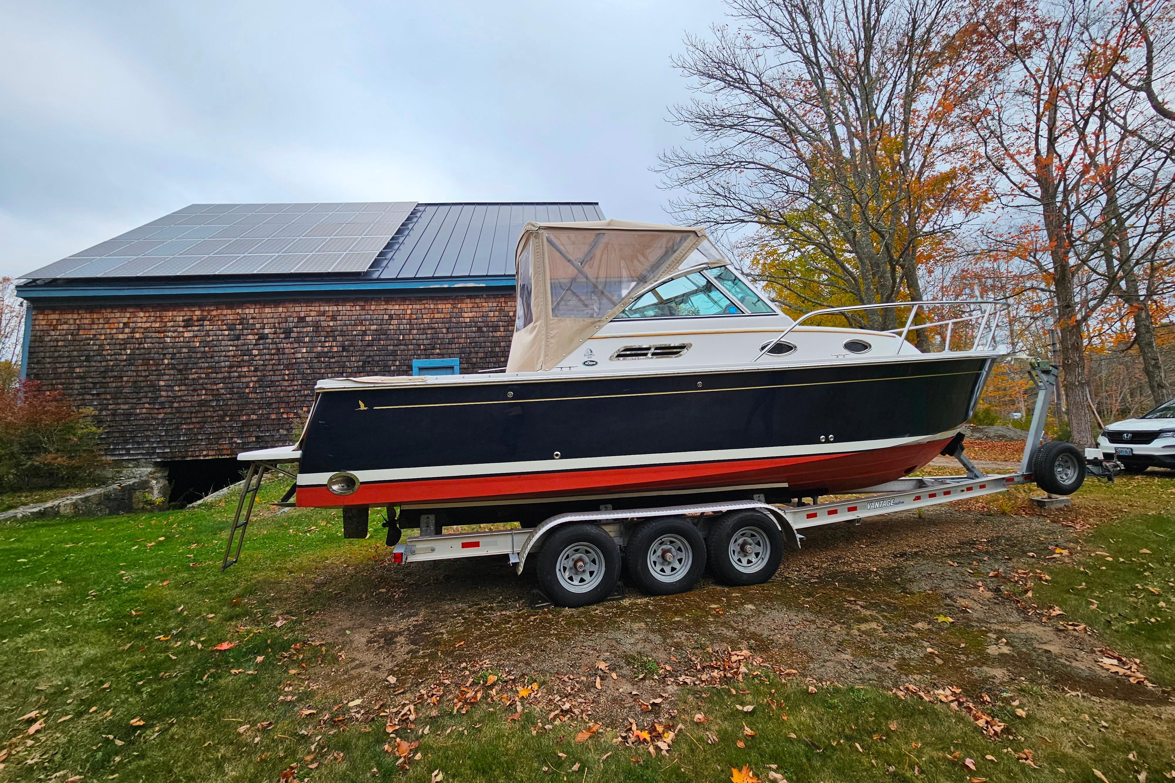 2006 Back Cove 26 boat on trailer, parked near a building with solar panels.