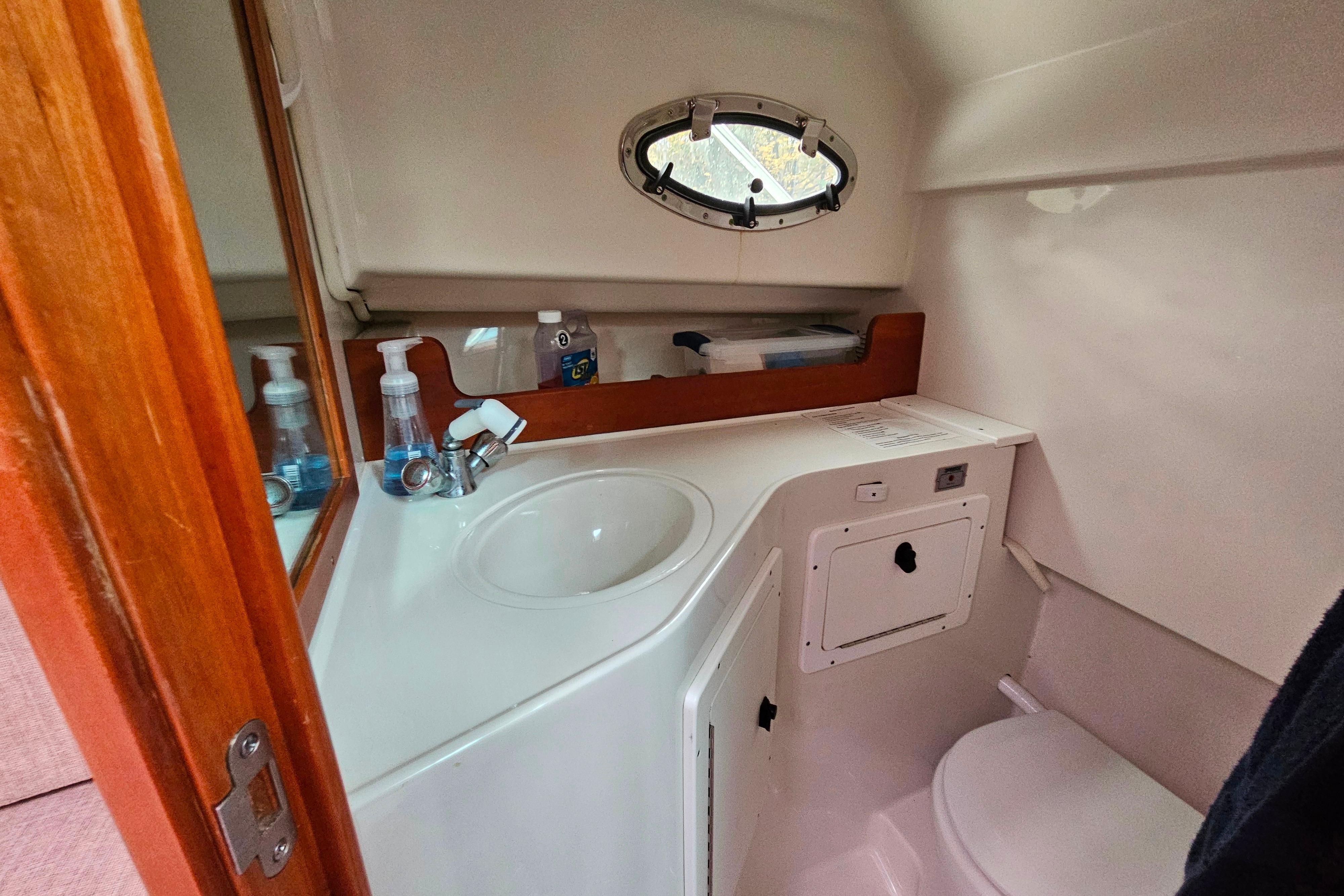 2006 Back Cove 26 boat bathroom with sink, mirror, and porthole window.