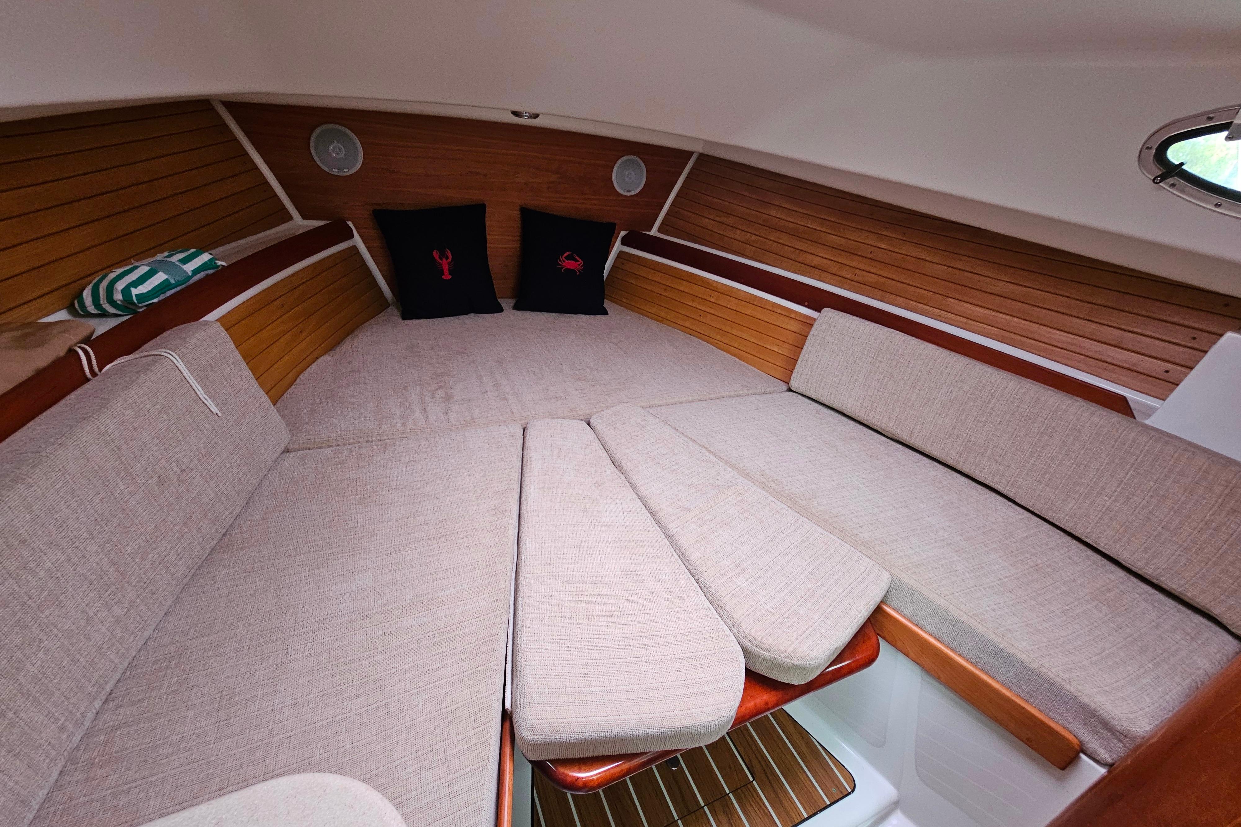 Cozy cabin interior of 2006 Back Cove 26 boat with cushions and wooden accents.