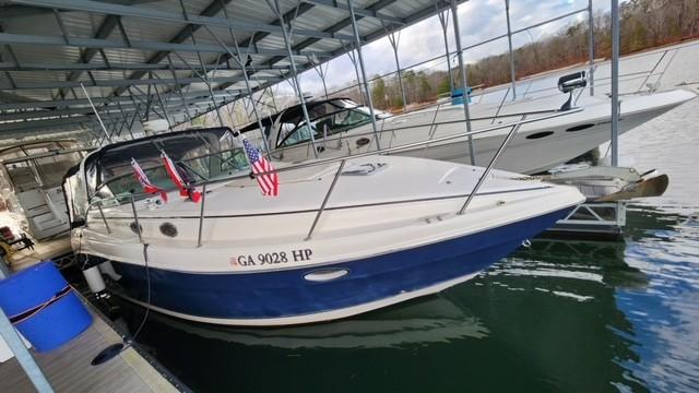 2005 Rinker Fiesta Vee 342 docked under a covered marina with flags displayed.