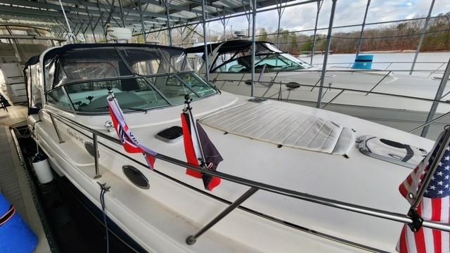 2005 Rinker Fiesta Vee 342 docked, featuring flags and covered seating area.
