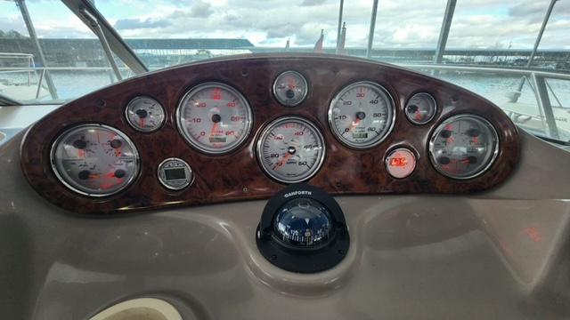 2005 Rinker Fiesta Vee 342 dashboard with gauges and compass, overlooking marina.