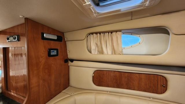 2005 Rinker Fiesta Vee 342 cabin interior with wood paneling and porthole window.