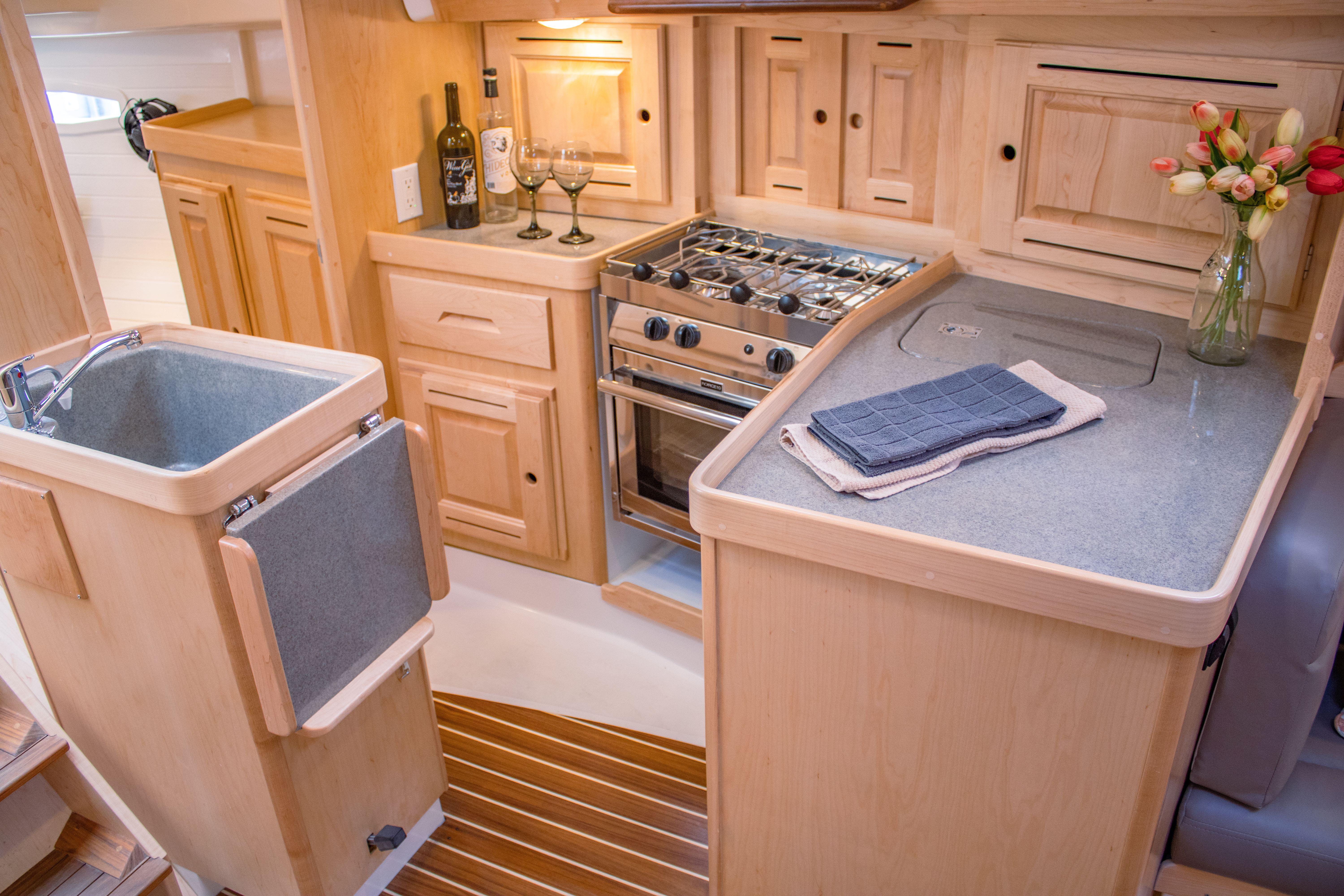 Tartan-365 2023-SEA #5 IN STOCK WA-US-Modern Tartan 365 yacht kitchen with wooden cabinetry, stove, and sink, 2023 model.-9568831 | Thumbnail