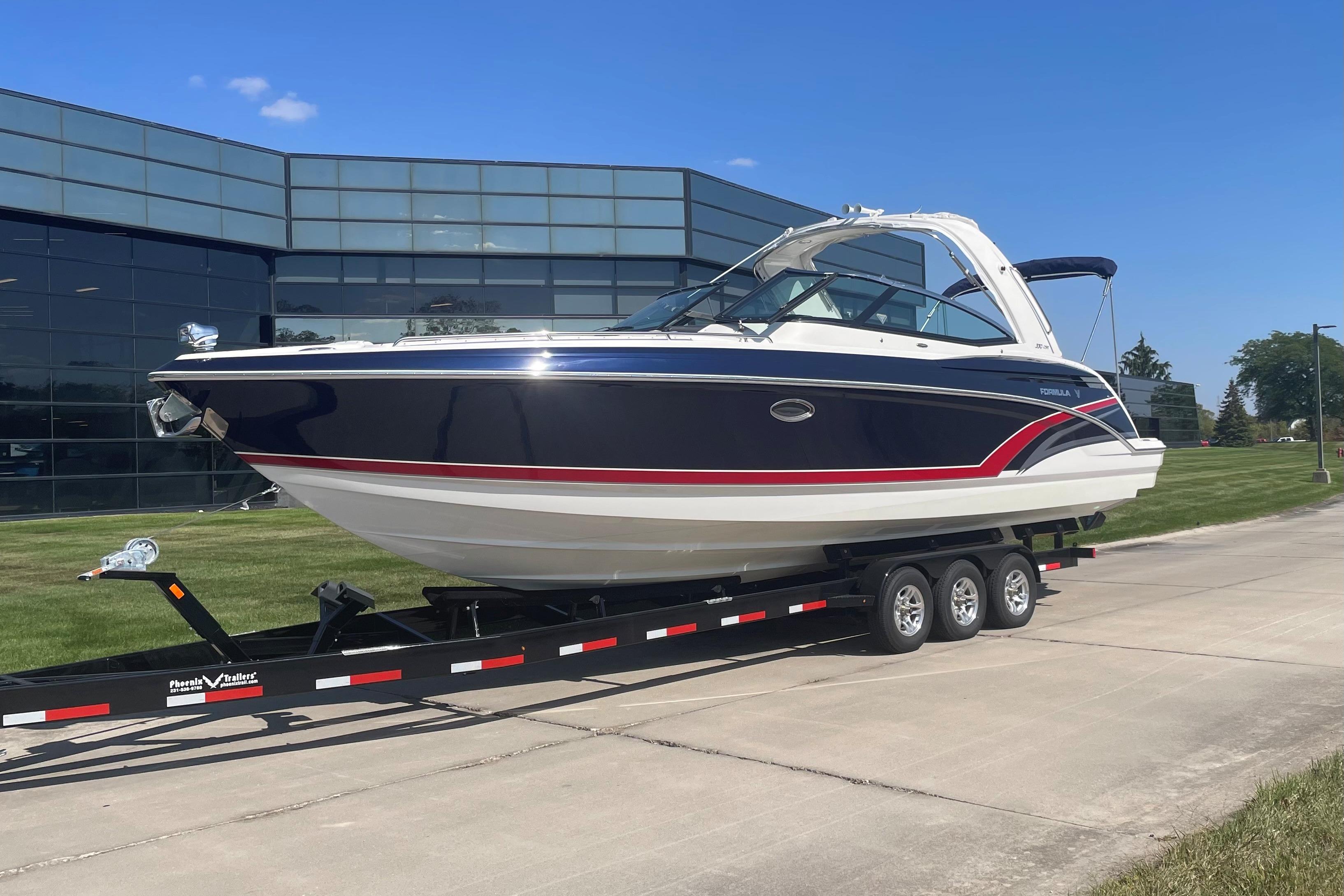 2016 Formula 330 Crossover Bowrider on trailer, parked near modern glass building.