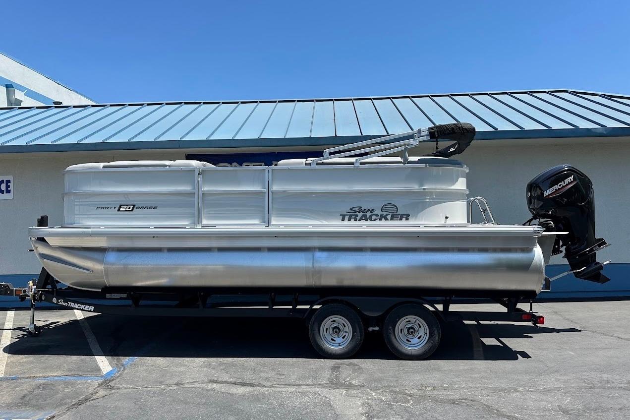 2026 Sun Tracker Party Barge 20 DLX pontoon boat on trailer, parked outdoors.