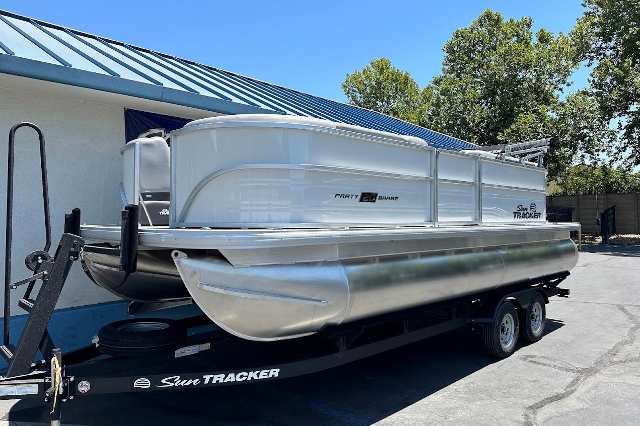 2026 Sun Tracker Party Barge 20 DLX pontoon boat on trailer, parked outdoors.