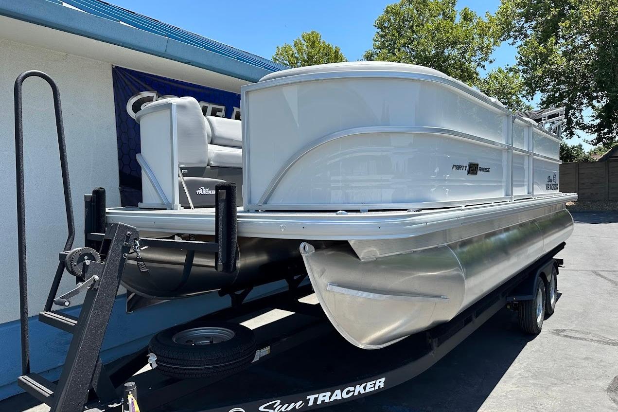 2026 Sun Tracker Party Barge 20 DLX pontoon boat on trailer, parked outdoors.