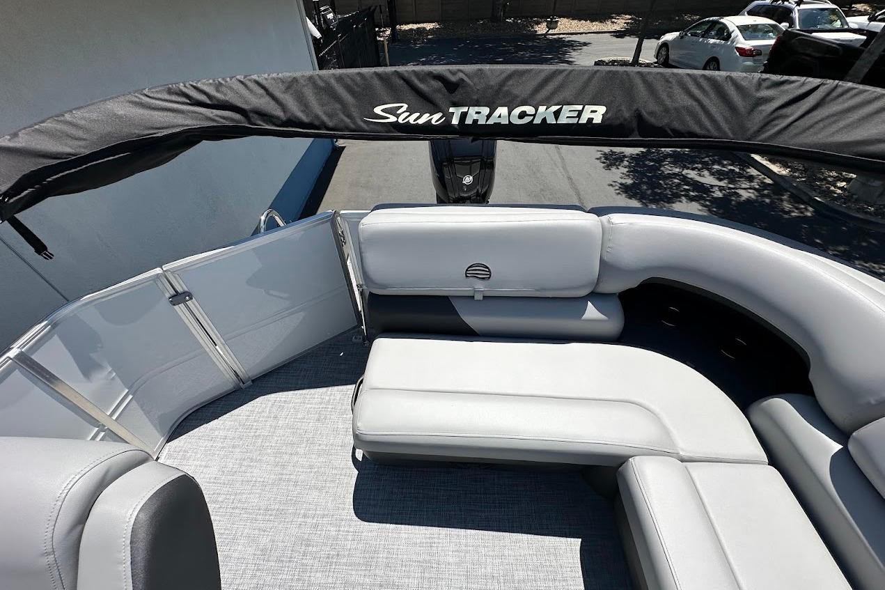2026 Sun Tracker Party Barge 20 DLX with gray seating and canopy, parked outdoors.