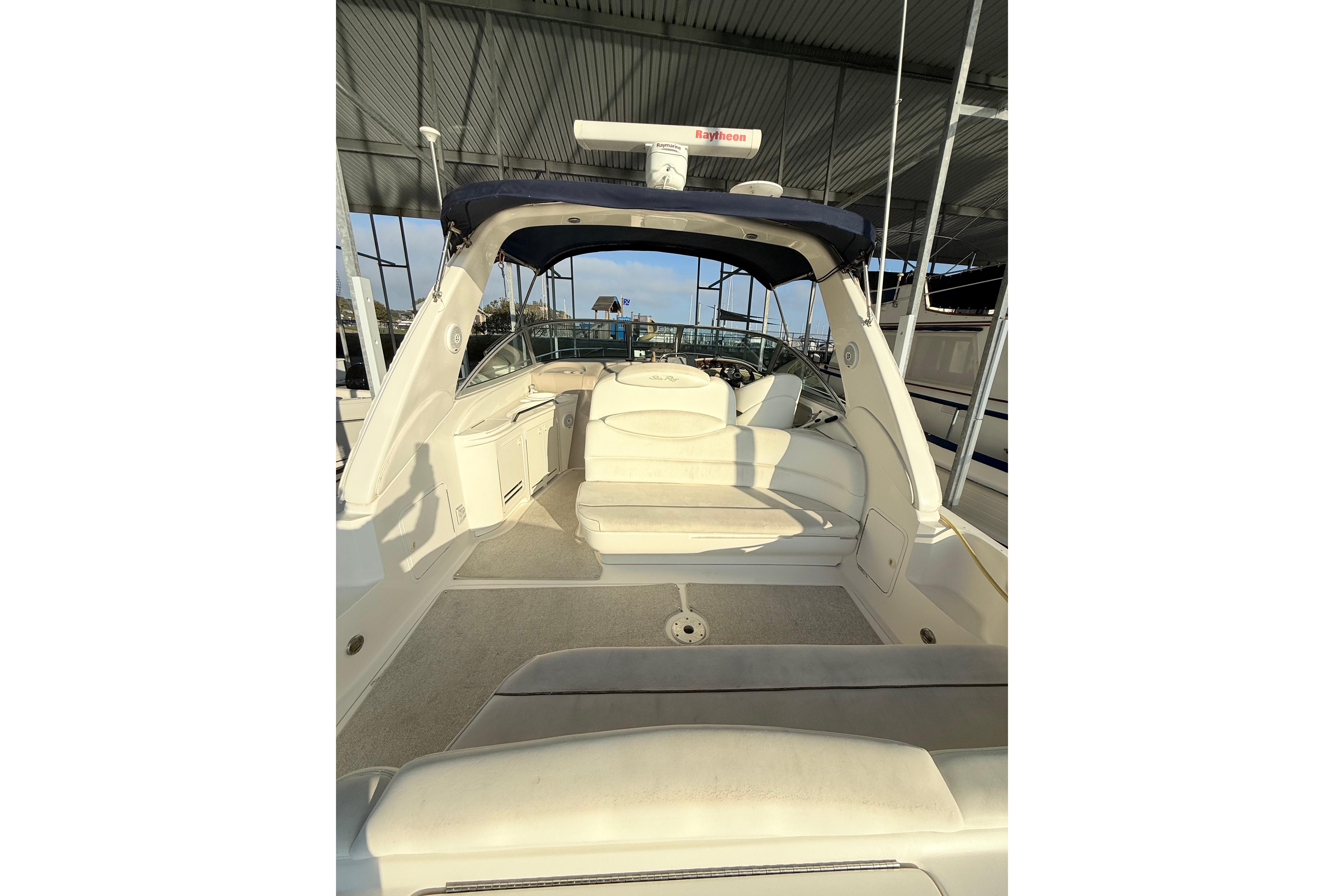 2001 Sea Ray 340 Sundancer boat interior with seating under a covered dock.