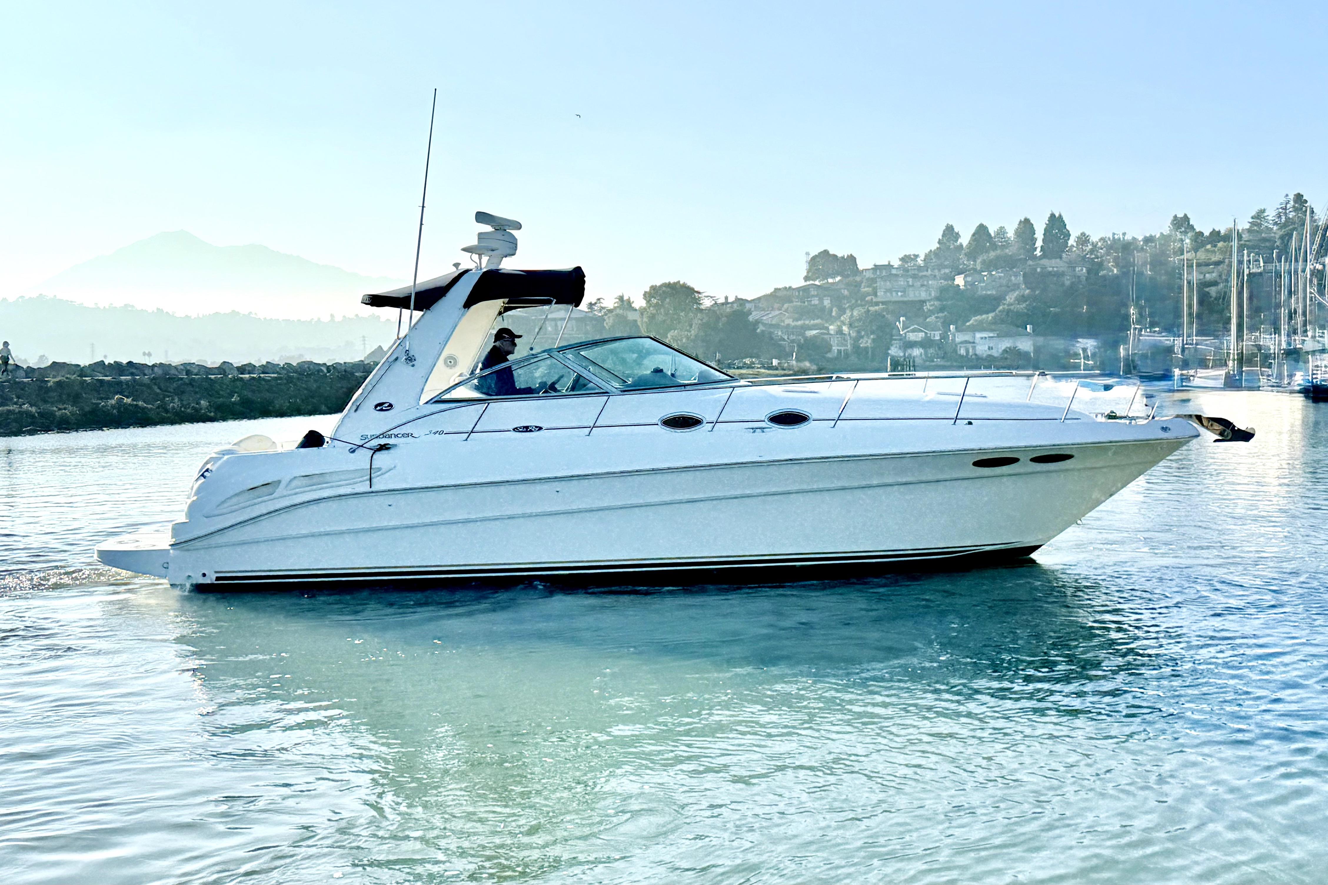 2001 Sea Ray 340 Sundancer yacht cruising on calm waters near a scenic shoreline.