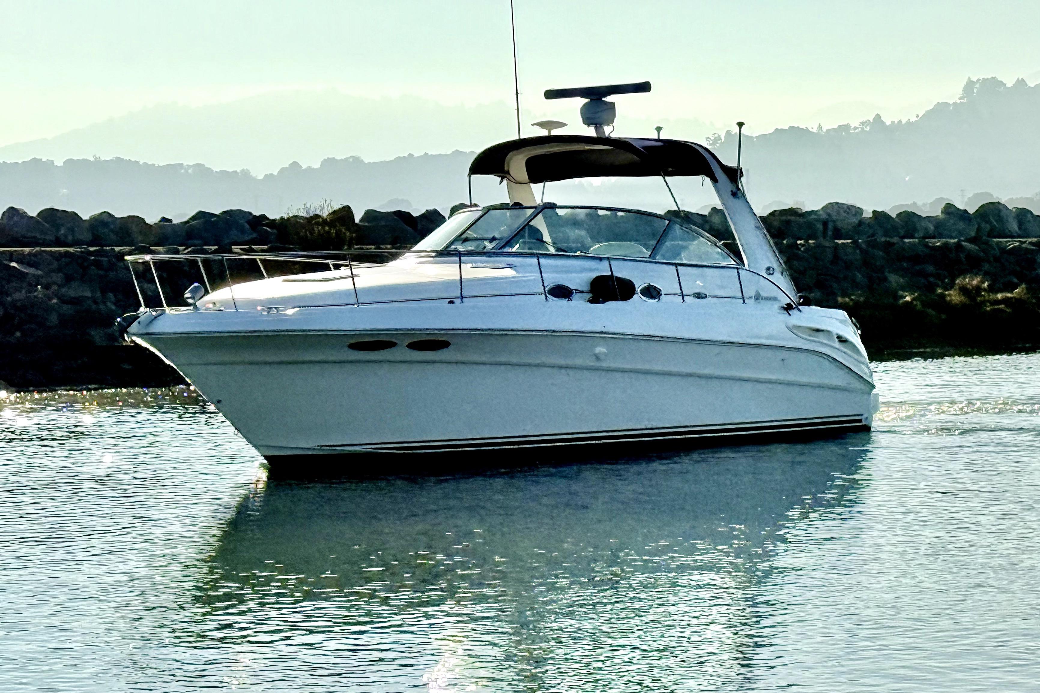 2001 Sea Ray 340 Sundancer yacht cruising on calm water with scenic background.
