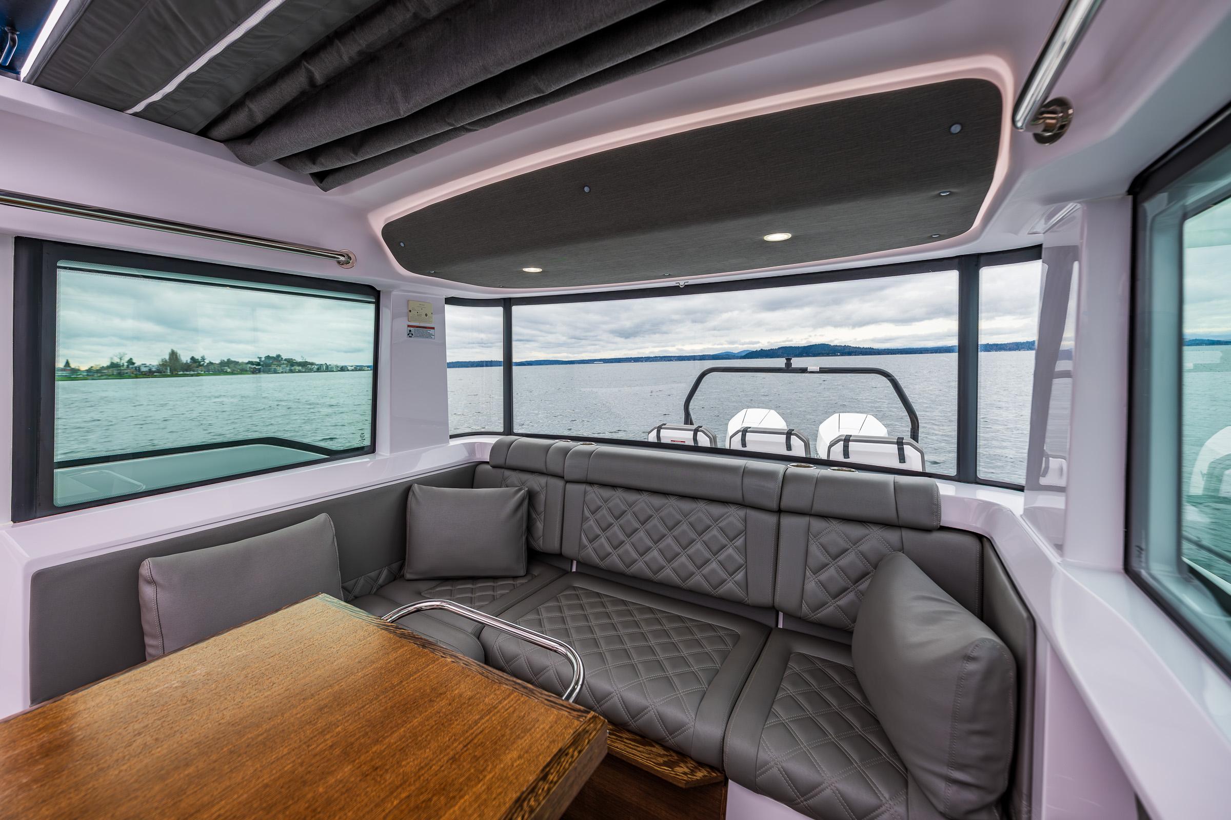 Axopar-37xc  Wetbar 2021-AQVAVIT WA-US-Interior of 2021 Axopar 37xc Wetbar with gray seating and wooden table, overlooking water.-9703795 | Thumbnail
