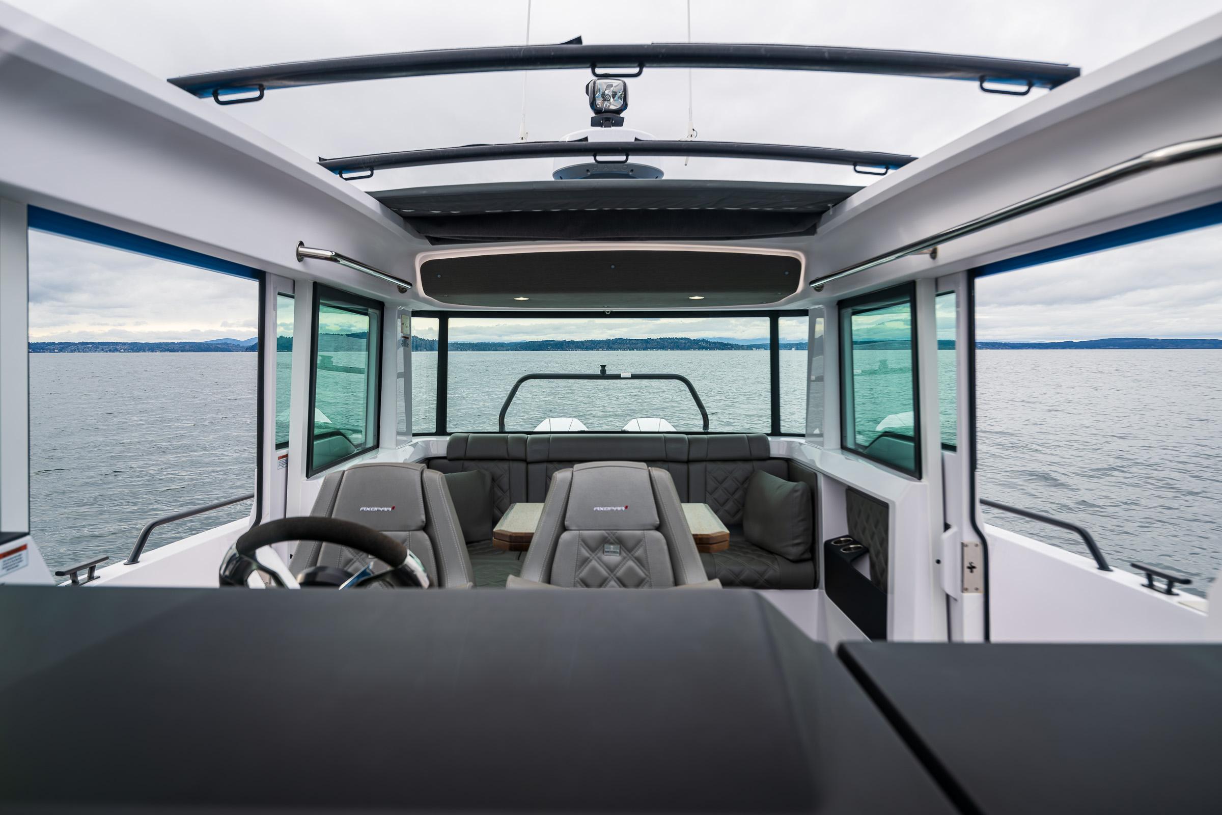 Axopar-37xc  Wetbar 2021-AQVAVIT WA-US-2021 Axopar 37xc Wetbar interior with seating, steering wheel, and panoramic windows on the water.-9703795 | Thumbnail