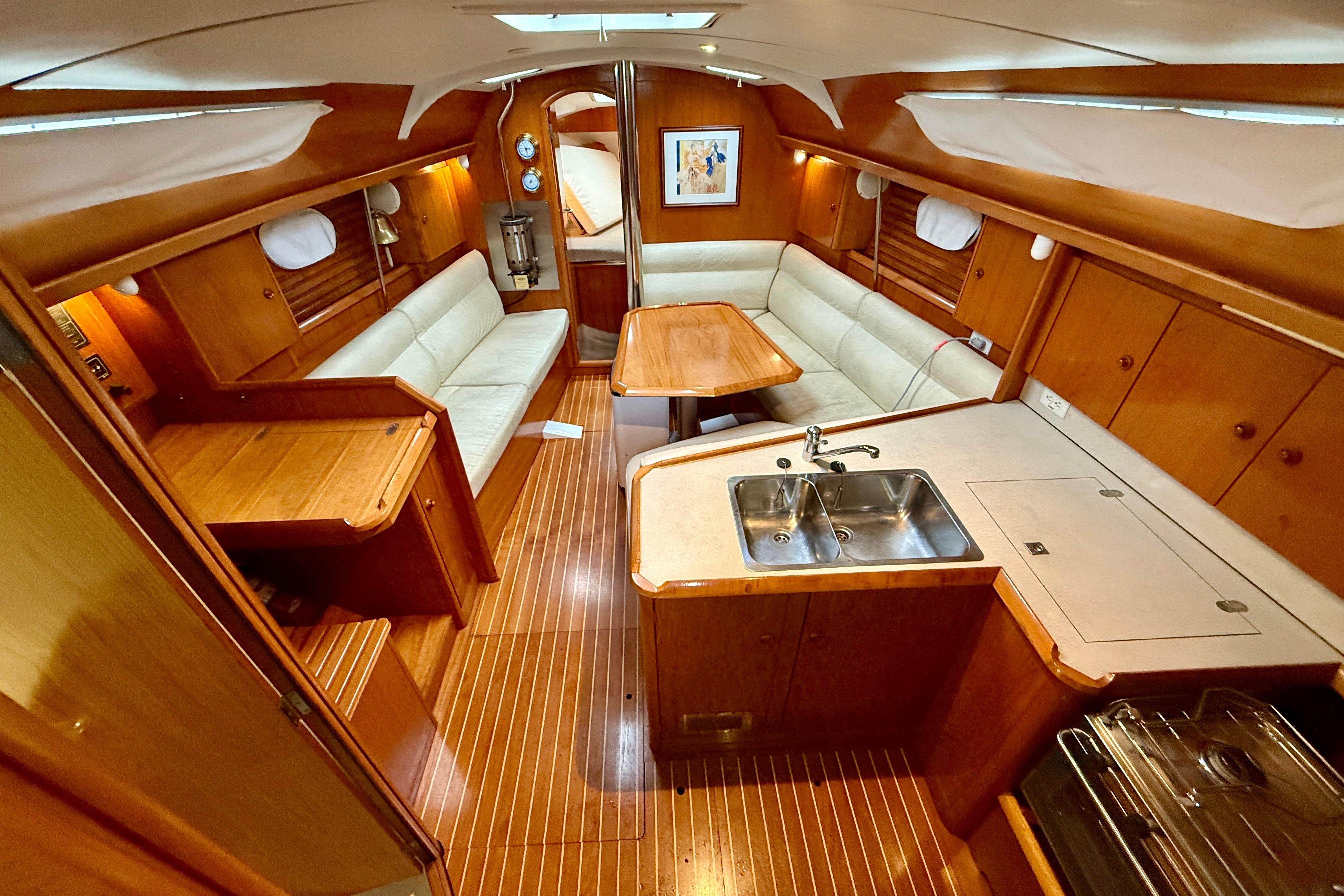 Interior of 1997 Jeanneau Sun Odyssey 36.2 sailboat with wood finish and cozy seating.