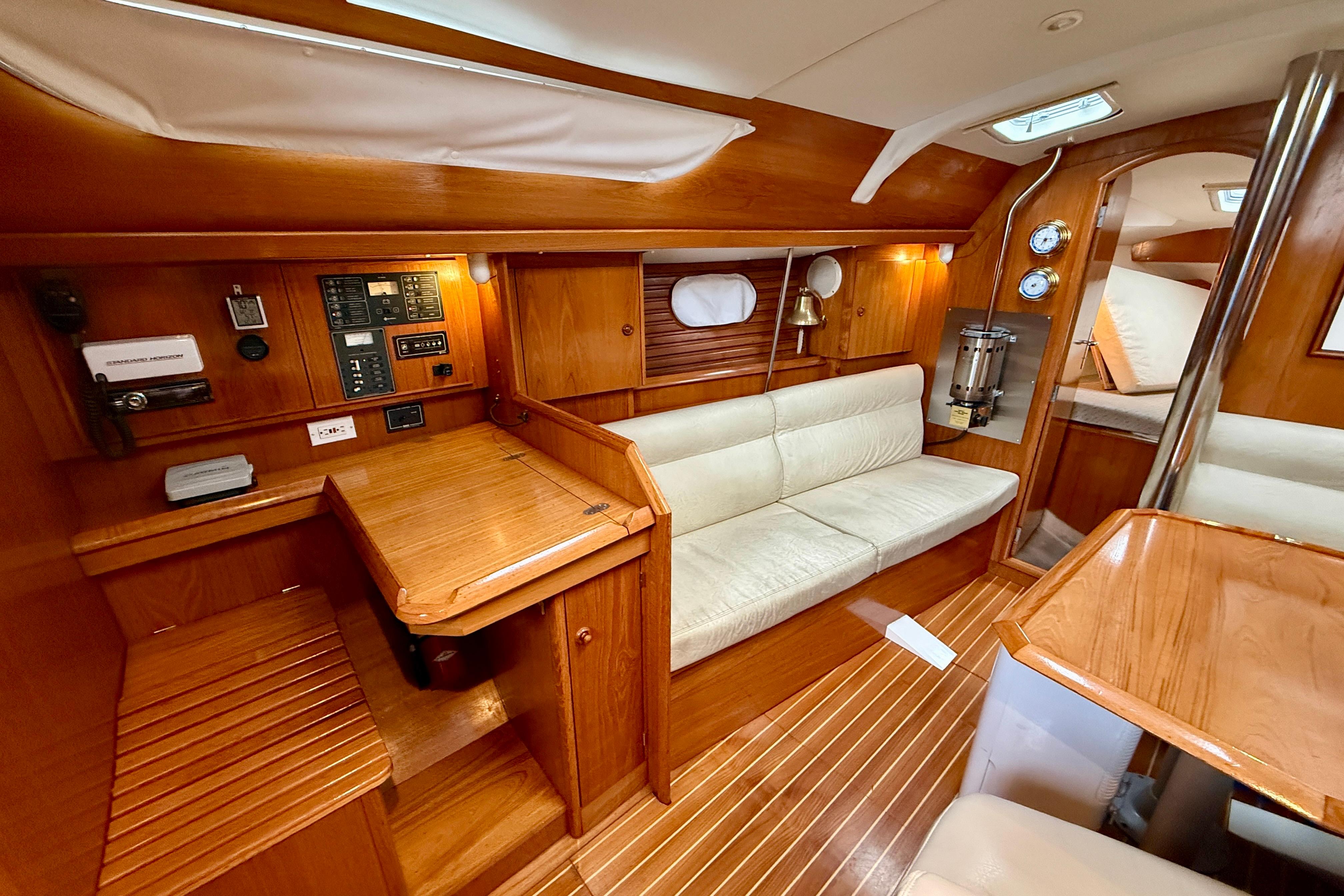 Interior of 1997 Jeanneau Sun Odyssey 36.2 sailboat with wooden furnishings and cozy seating.