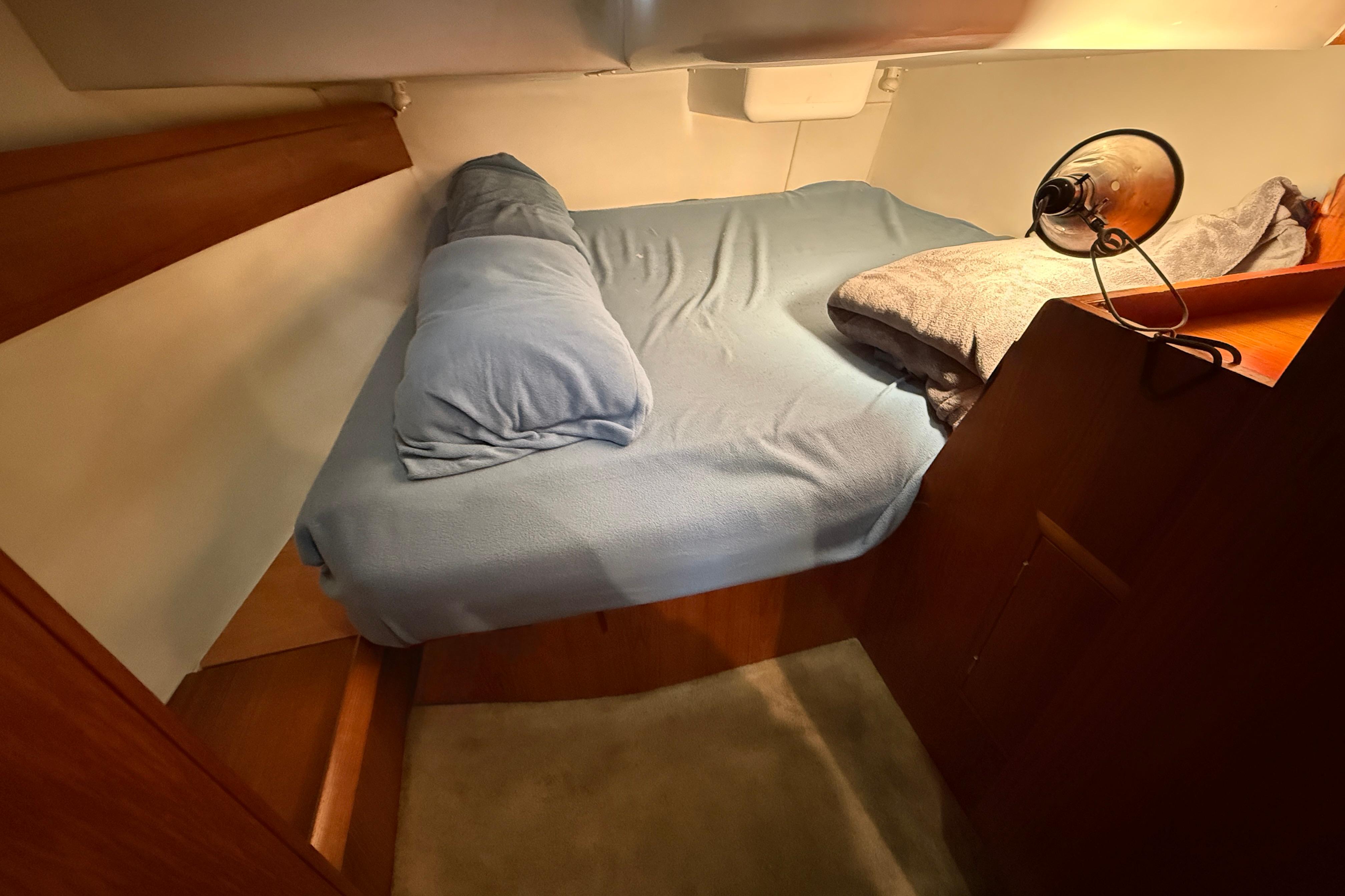 Cozy cabin interior of 1997 Jeanneau Sun Odyssey 36.2 sailboat with bed and reading lamp.