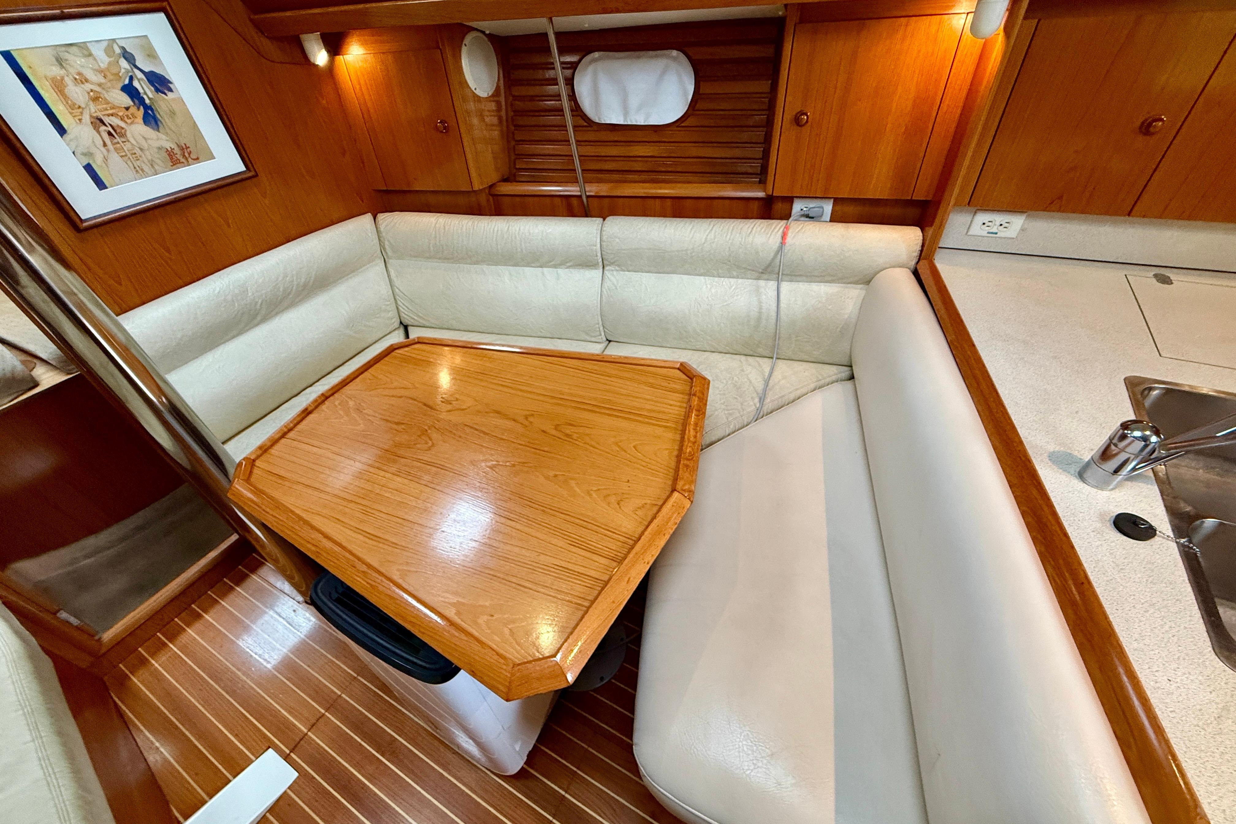 Interior of 1997 Jeanneau Sun Odyssey 36.2 sailboat with cozy dining area and wooden table.