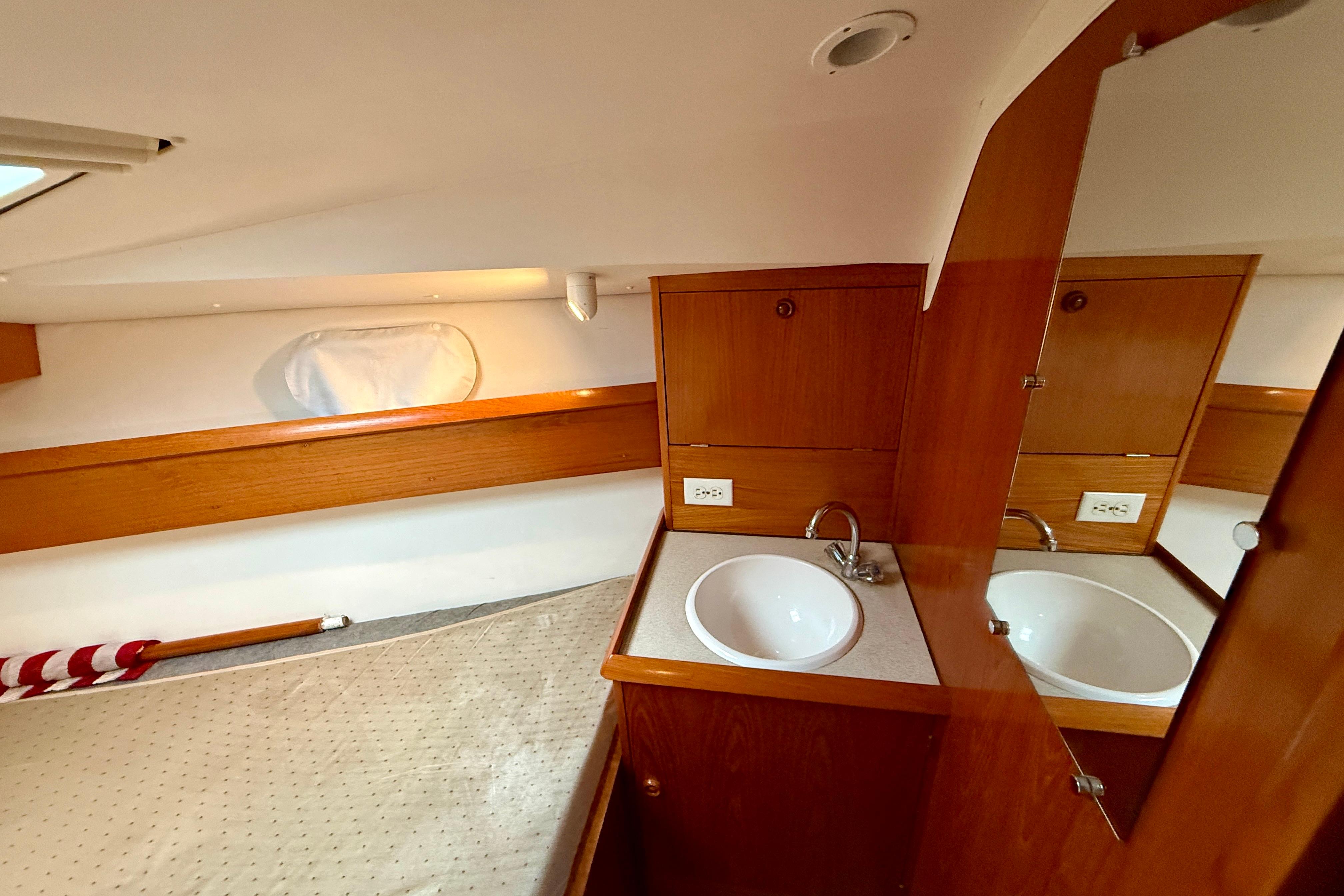 Interior of 1997 Jeanneau Sun Odyssey 36.2 yacht with wooden cabinetry and sink.