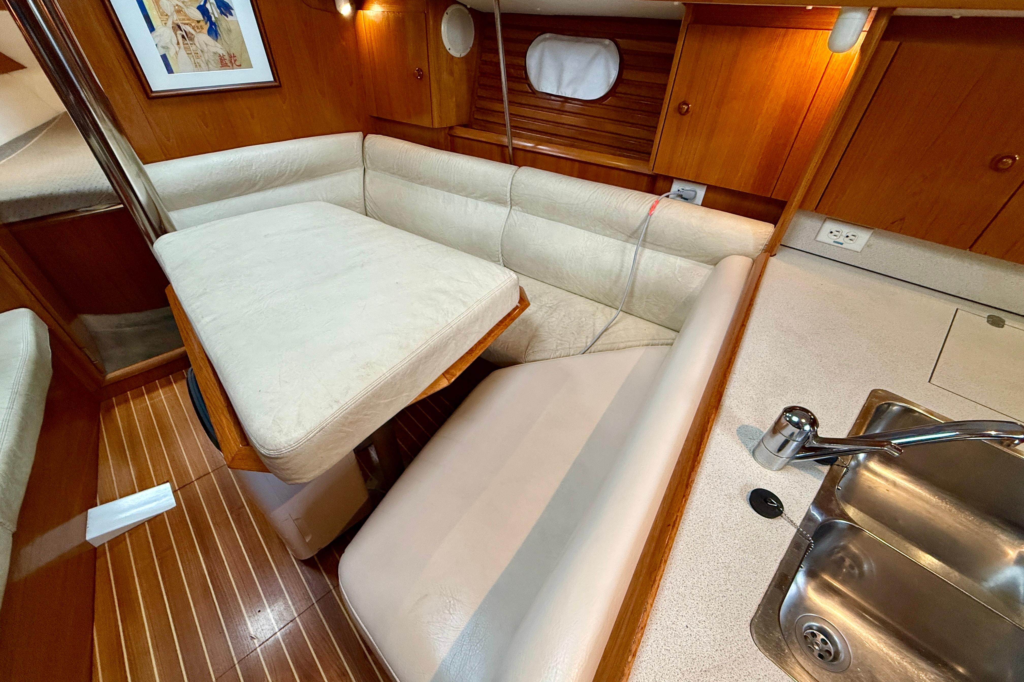 Cozy interior of 1997 Jeanneau Sun Odyssey 36.2 sailboat with dining area and kitchenette.