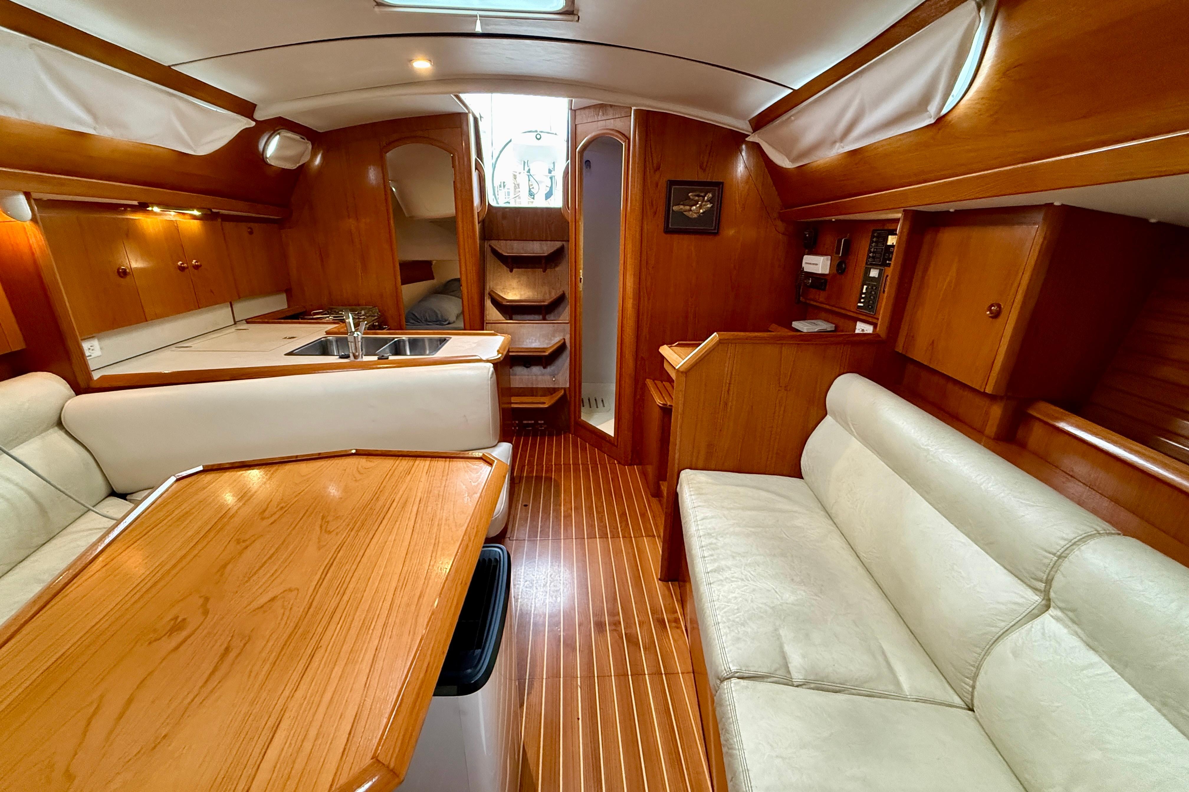 Interior of 1997 Jeanneau Sun Odyssey 36.2 sailboat with wood finish and cozy seating.
