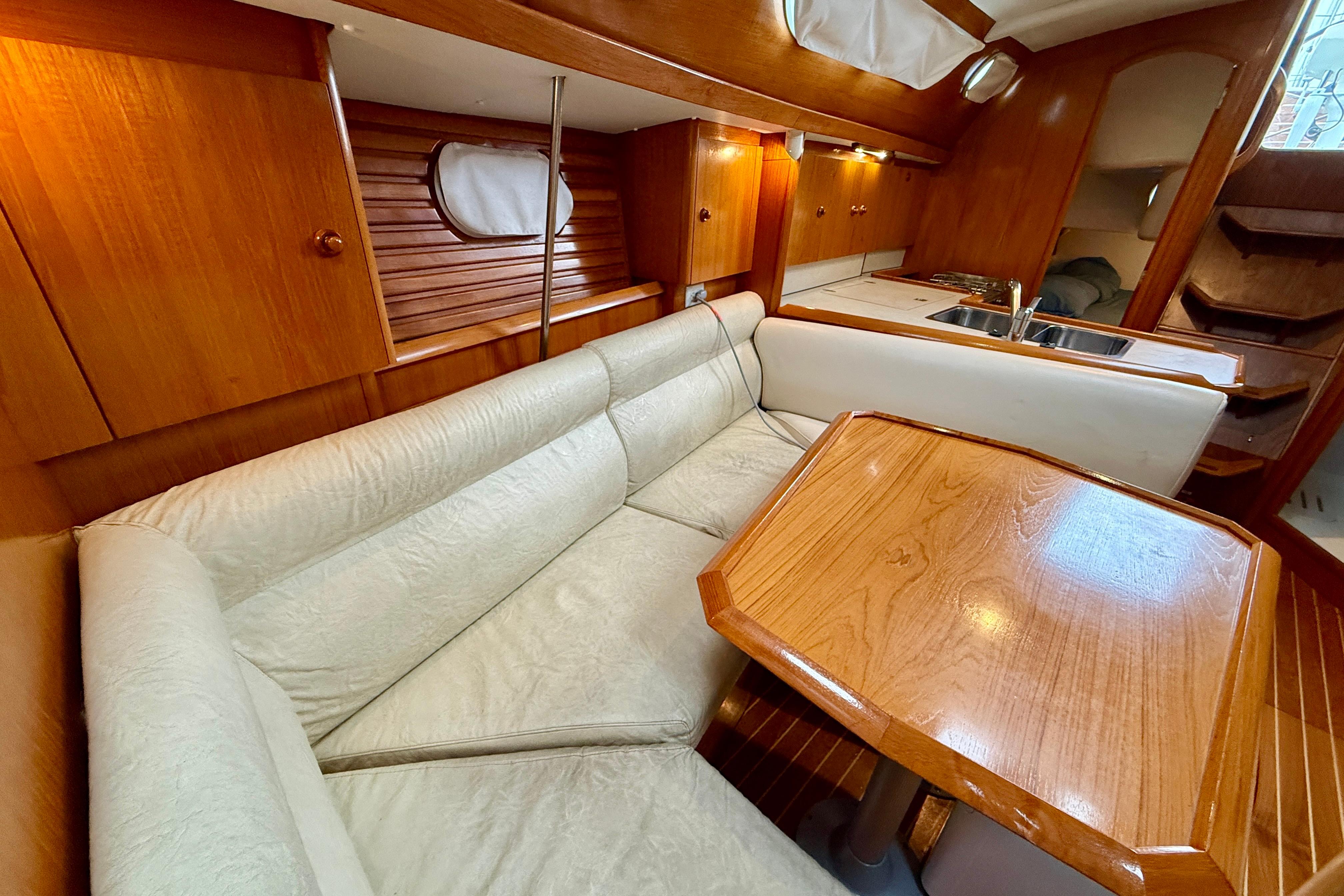 Cozy interior of 1997 Jeanneau Sun Odyssey 36.2 sailboat with wooden finishes and seating area.