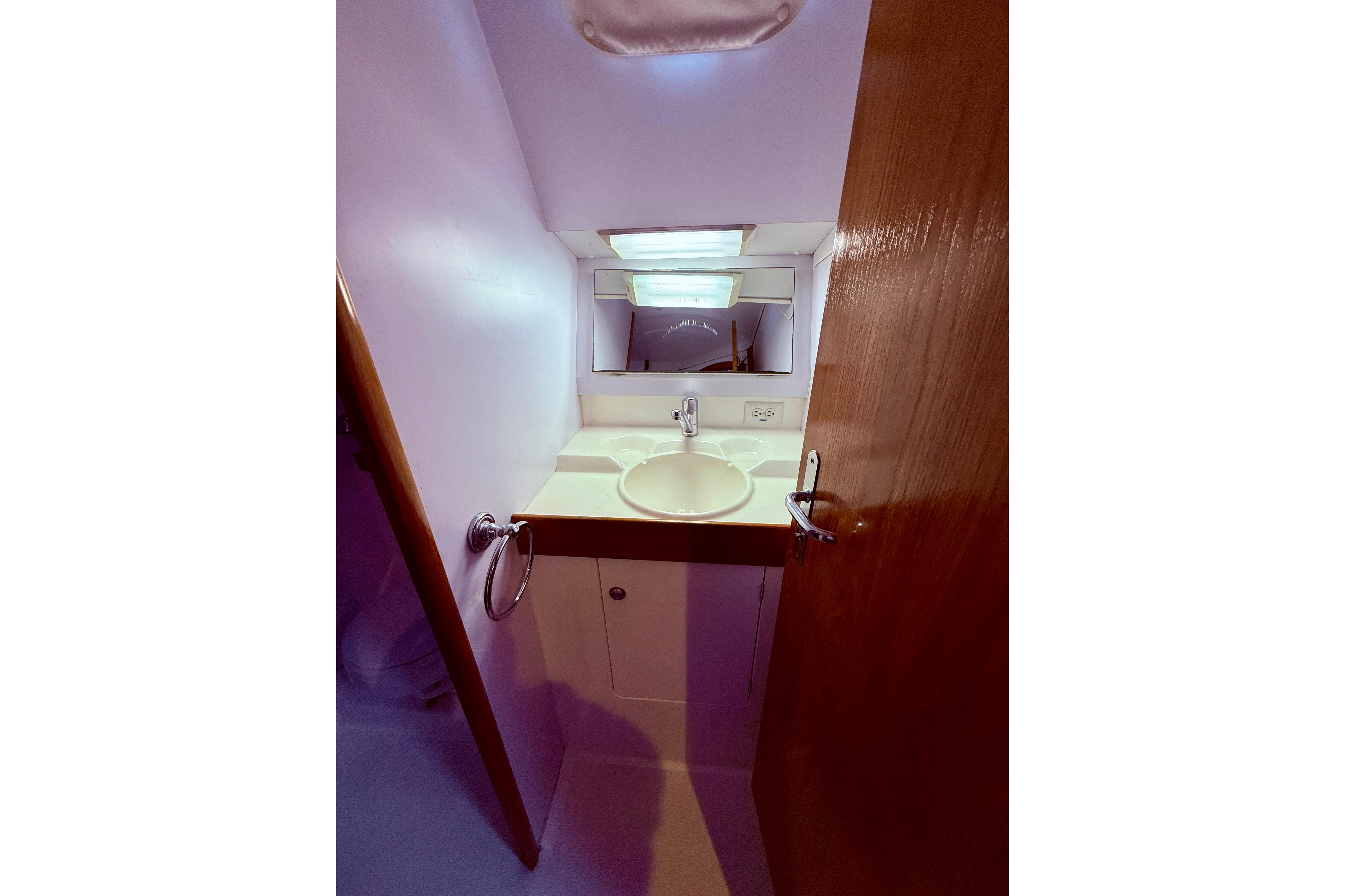 Compact bathroom in 1997 Jeanneau Sun Odyssey 36.2 sailboat with sink and mirror.