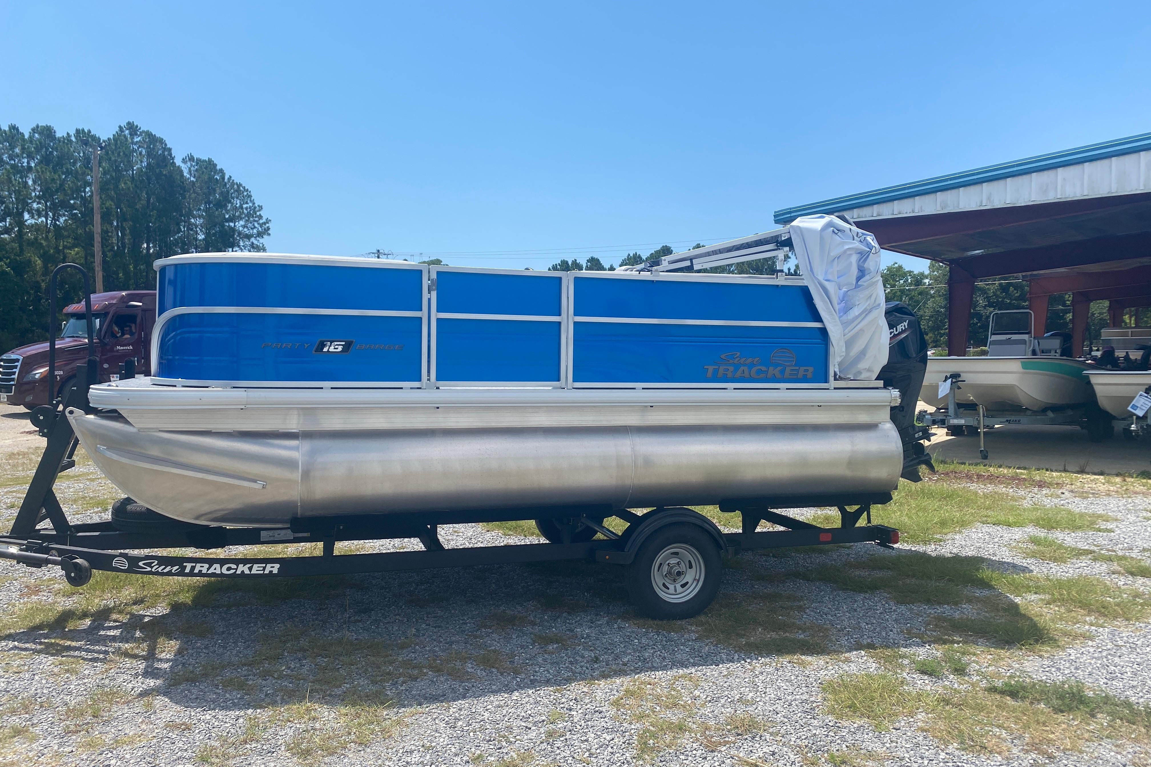 2026 Sun Tracker Party Barge 16 DLX pontoon boat on trailer, parked outdoors.