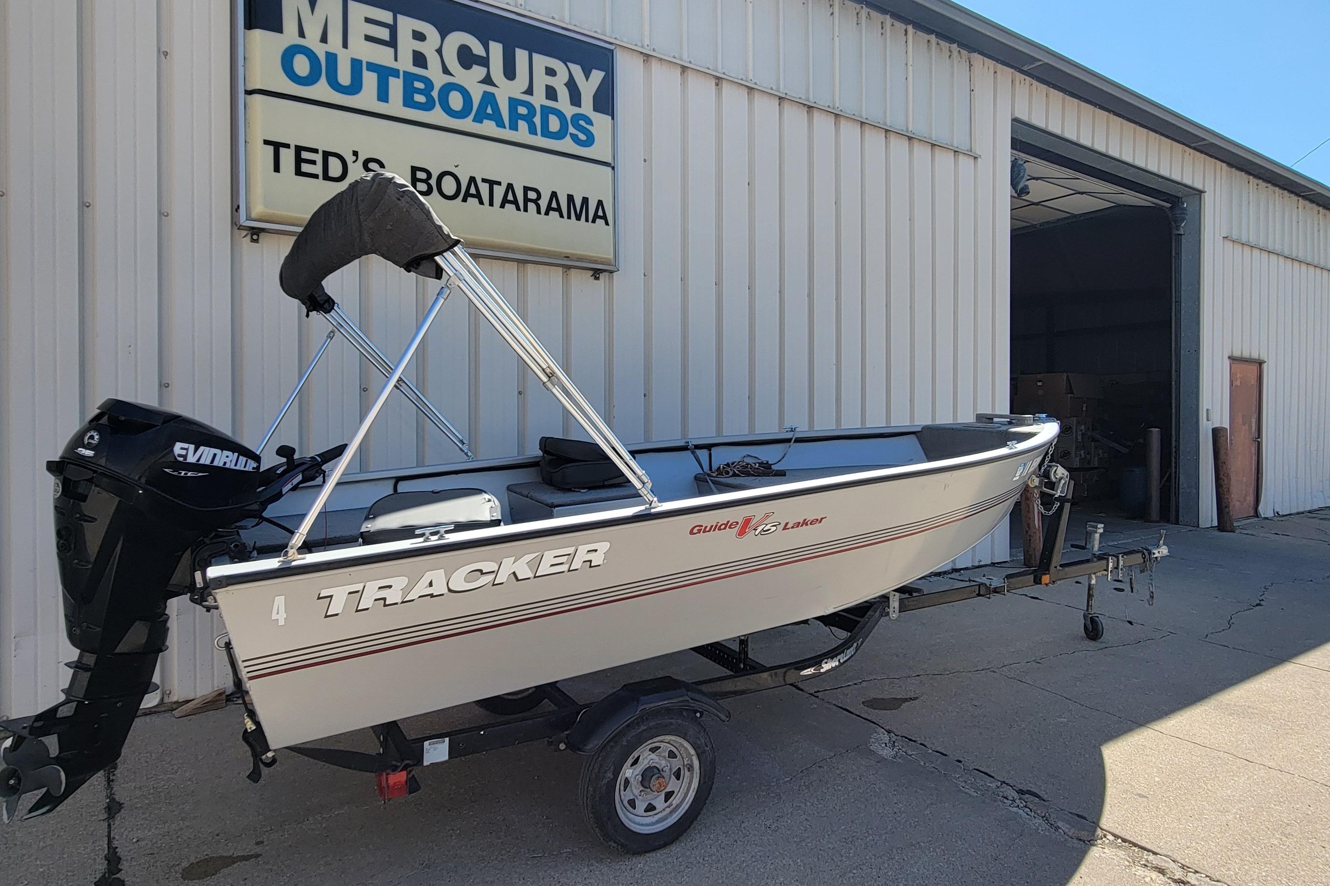 2010 Tracker Guide V 15 Laker boat on trailer outside Mercury Outboards shop.