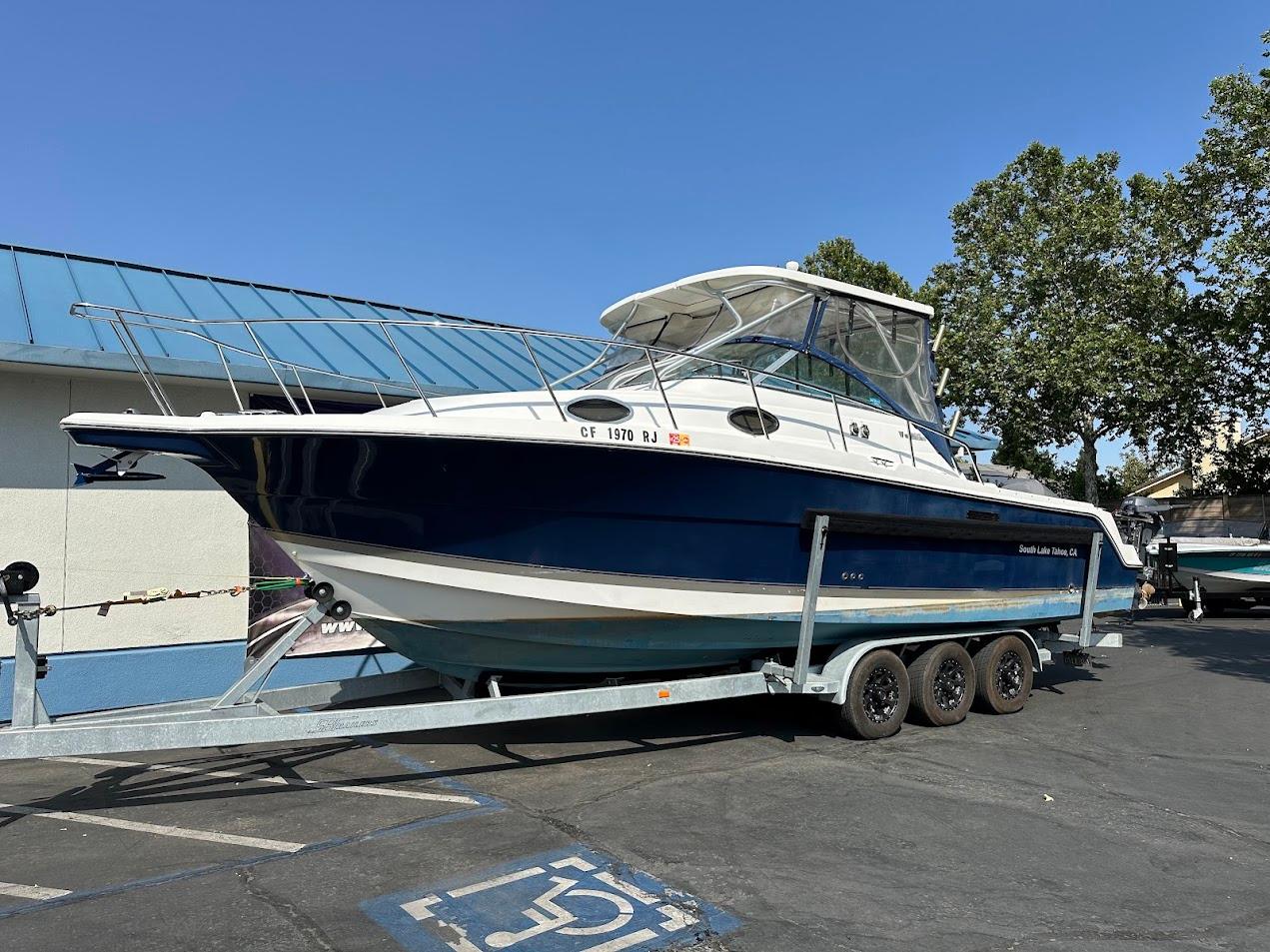 2006 Wellcraft 290 Coastal boat on trailer, parked outdoors, blue and white design.