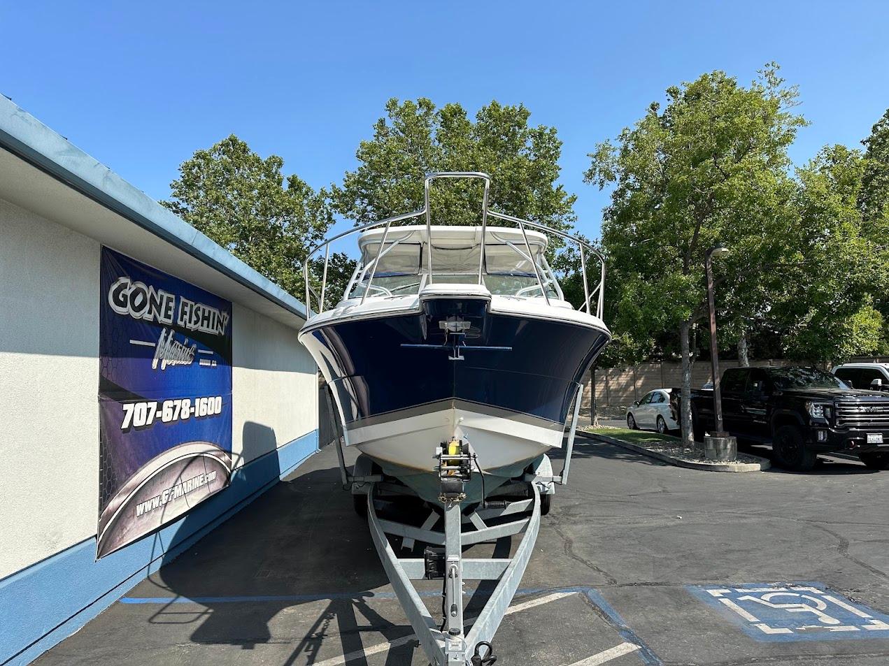 2006 Wellcraft 290 Coastal boat on trailer, parked near a building with trees in the background.