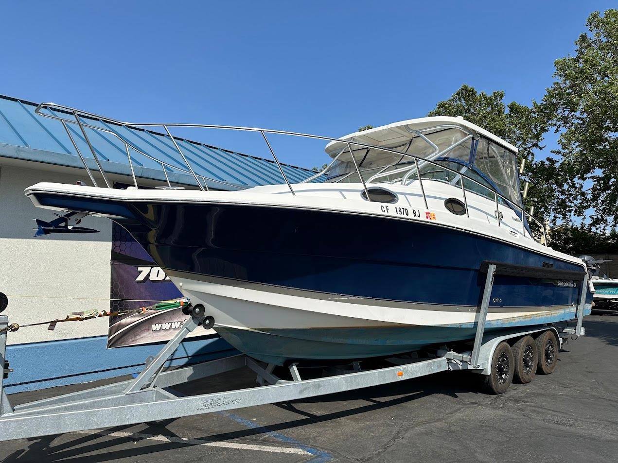 2006 Wellcraft 290 Coastal boat on trailer, blue and white exterior, parked outdoors.
