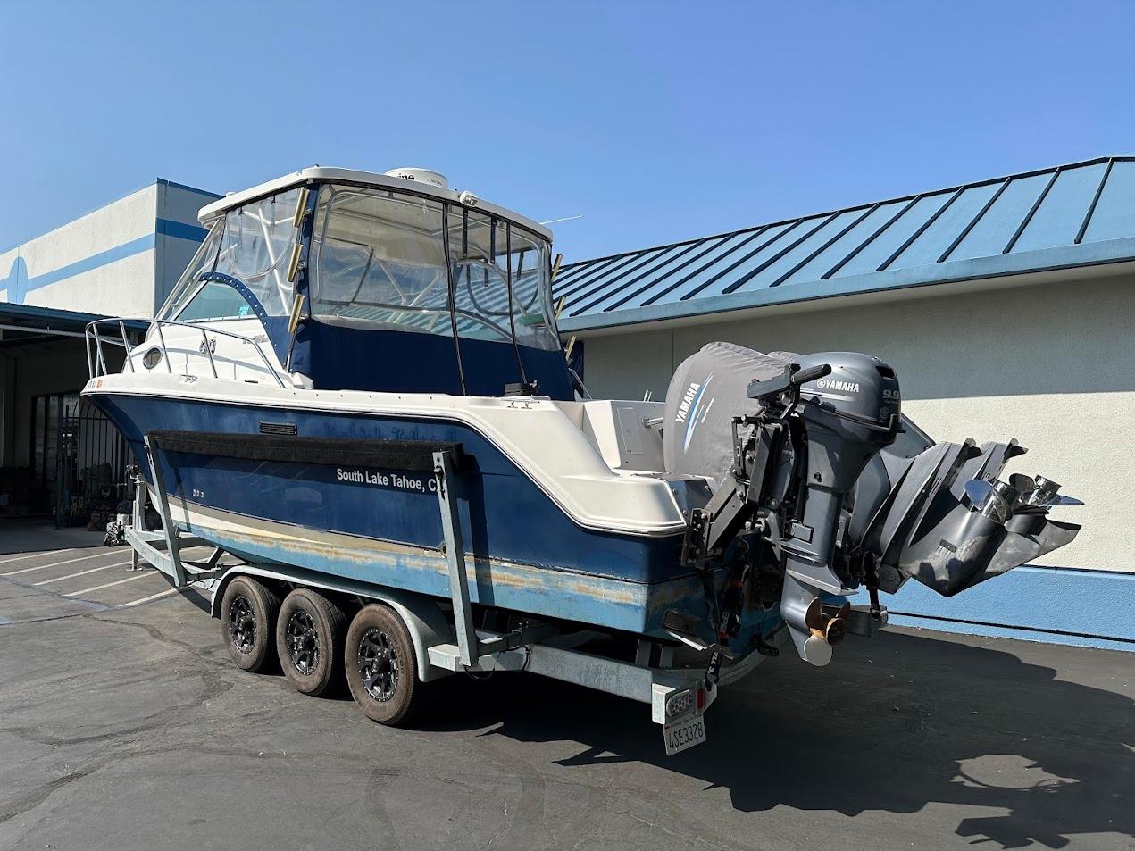 2006 Wellcraft 290 Coastal boat on trailer, parked outdoors, featuring dual outboard engines.