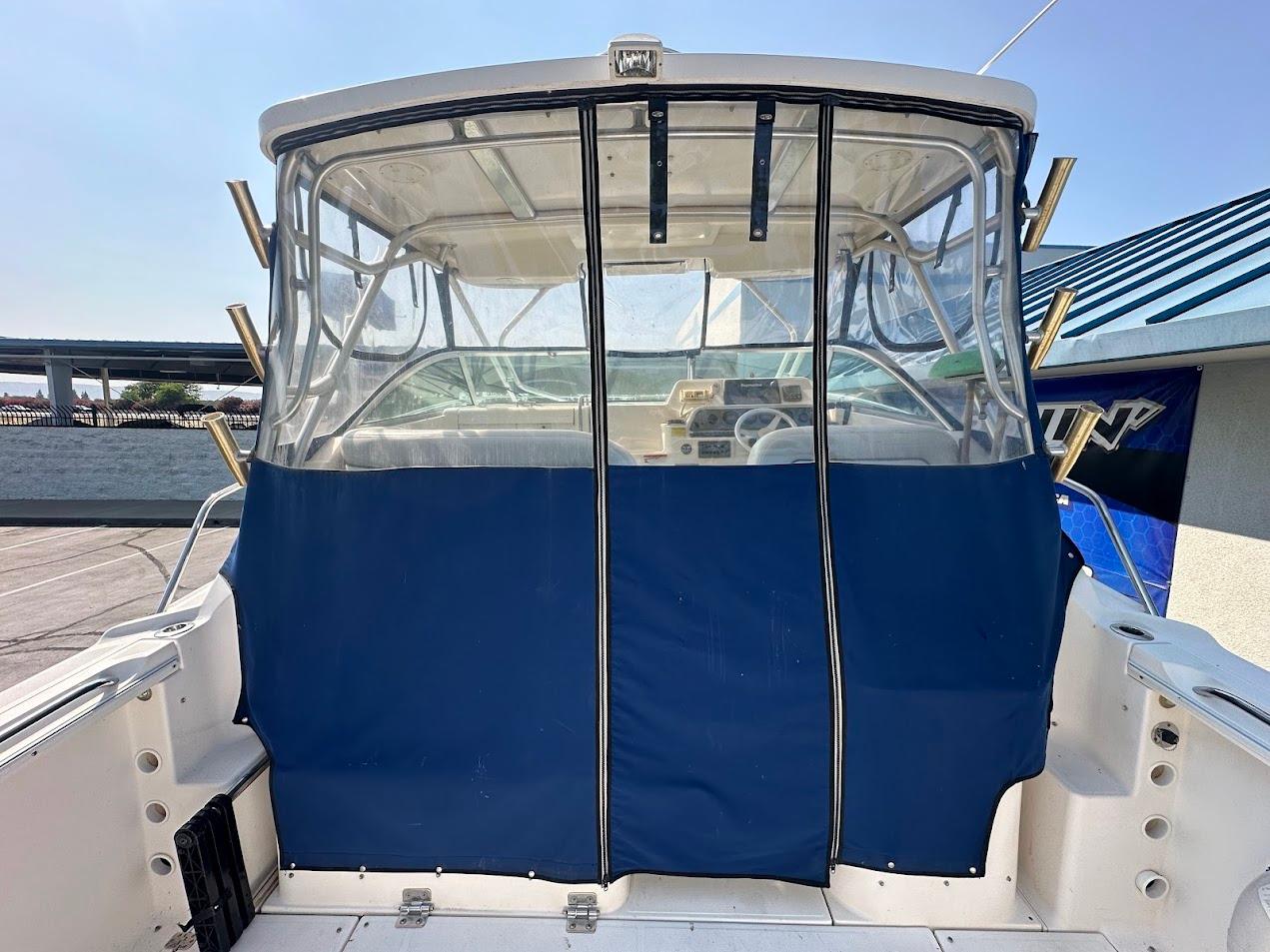 2006 Wellcraft 290 Coastal boat with blue canvas enclosure and clear windows.