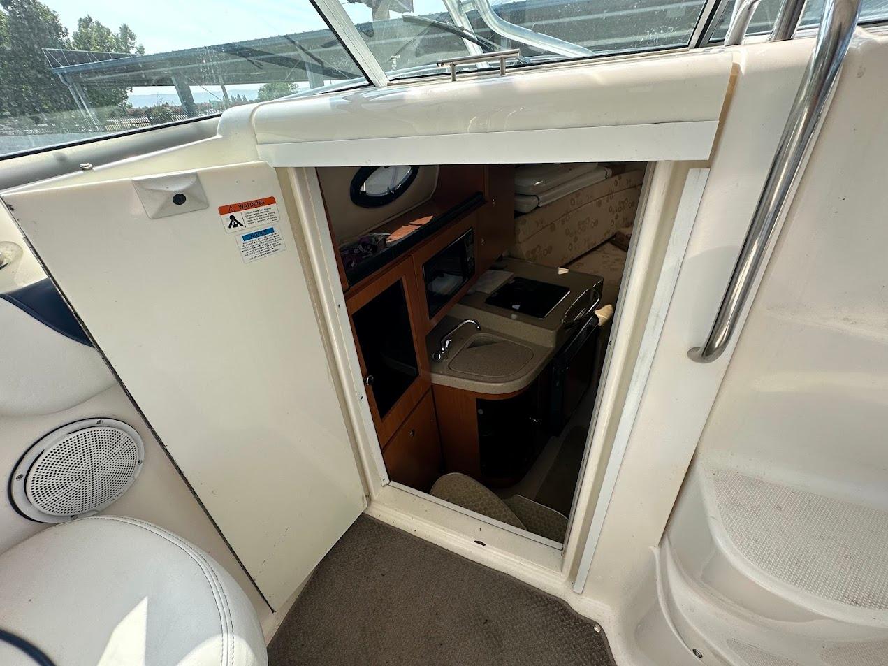 Interior view of 2006 Wellcraft 290 Coastal boat cabin with kitchenette and seating area.