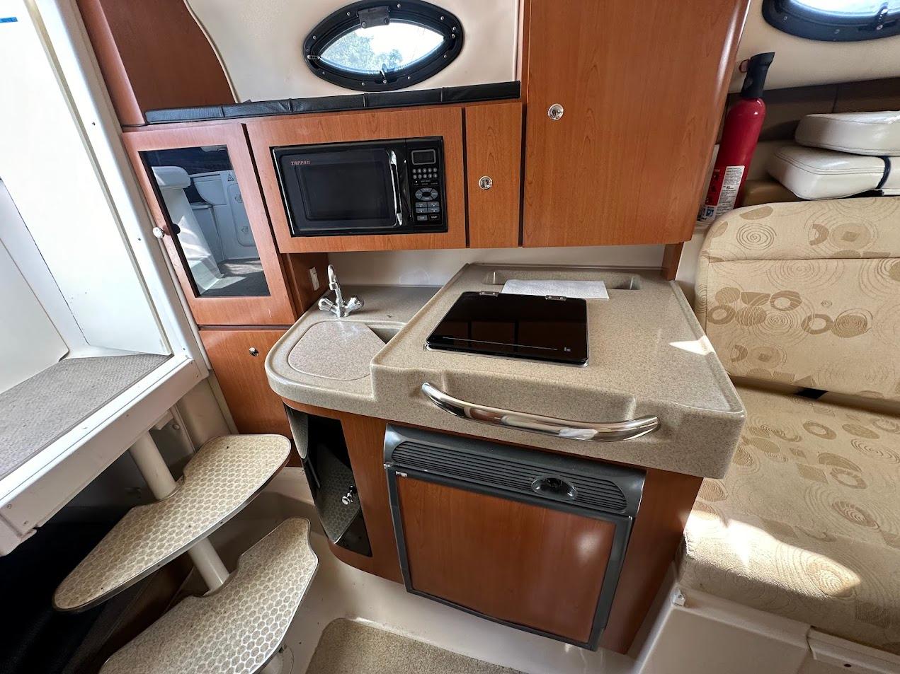 2006 Wellcraft 290 Coastal interior with kitchenette, microwave, sink, and seating area.