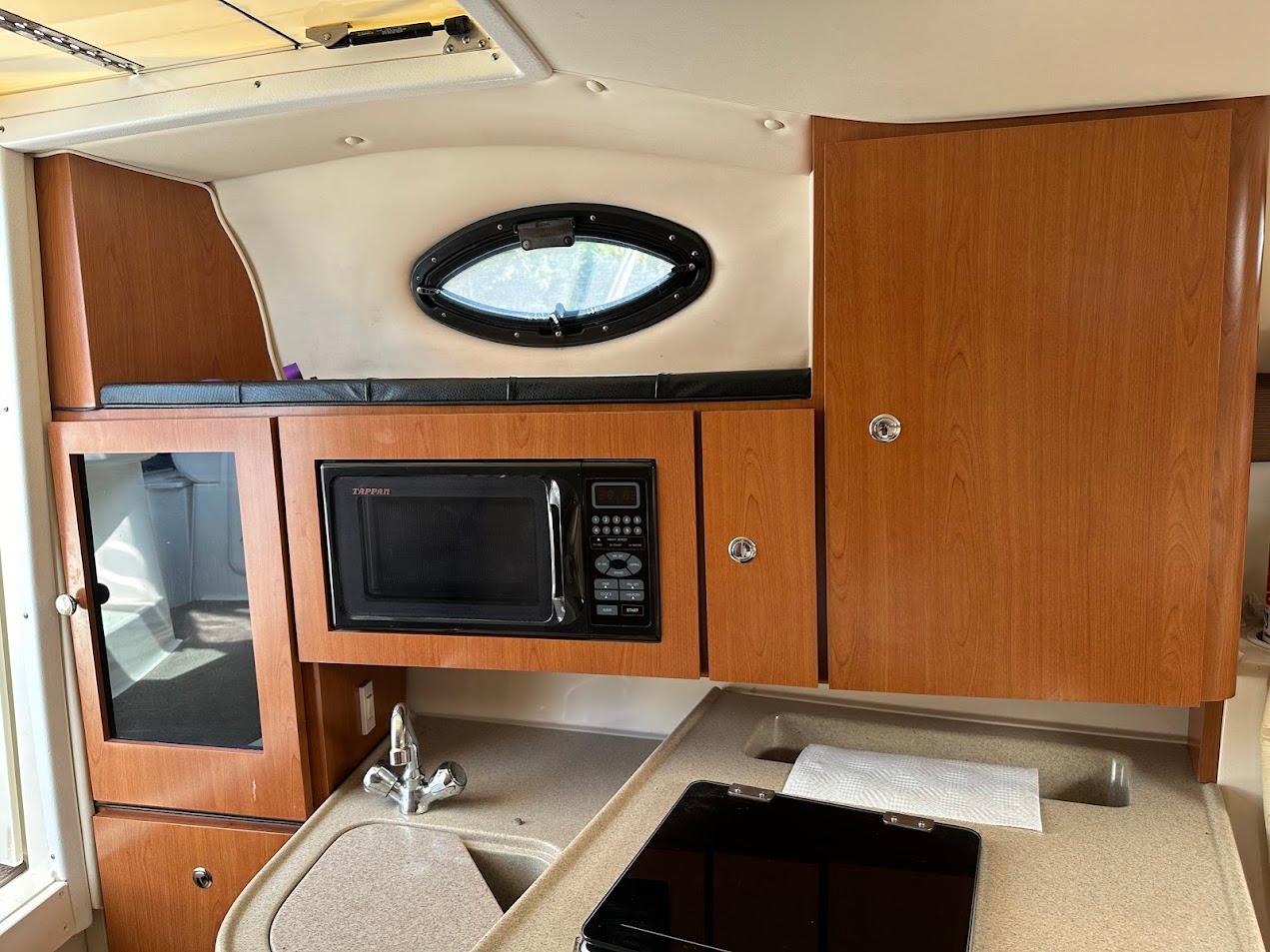 2006 Wellcraft 290 Coastal boat interior with microwave, sink, and wooden cabinets.
