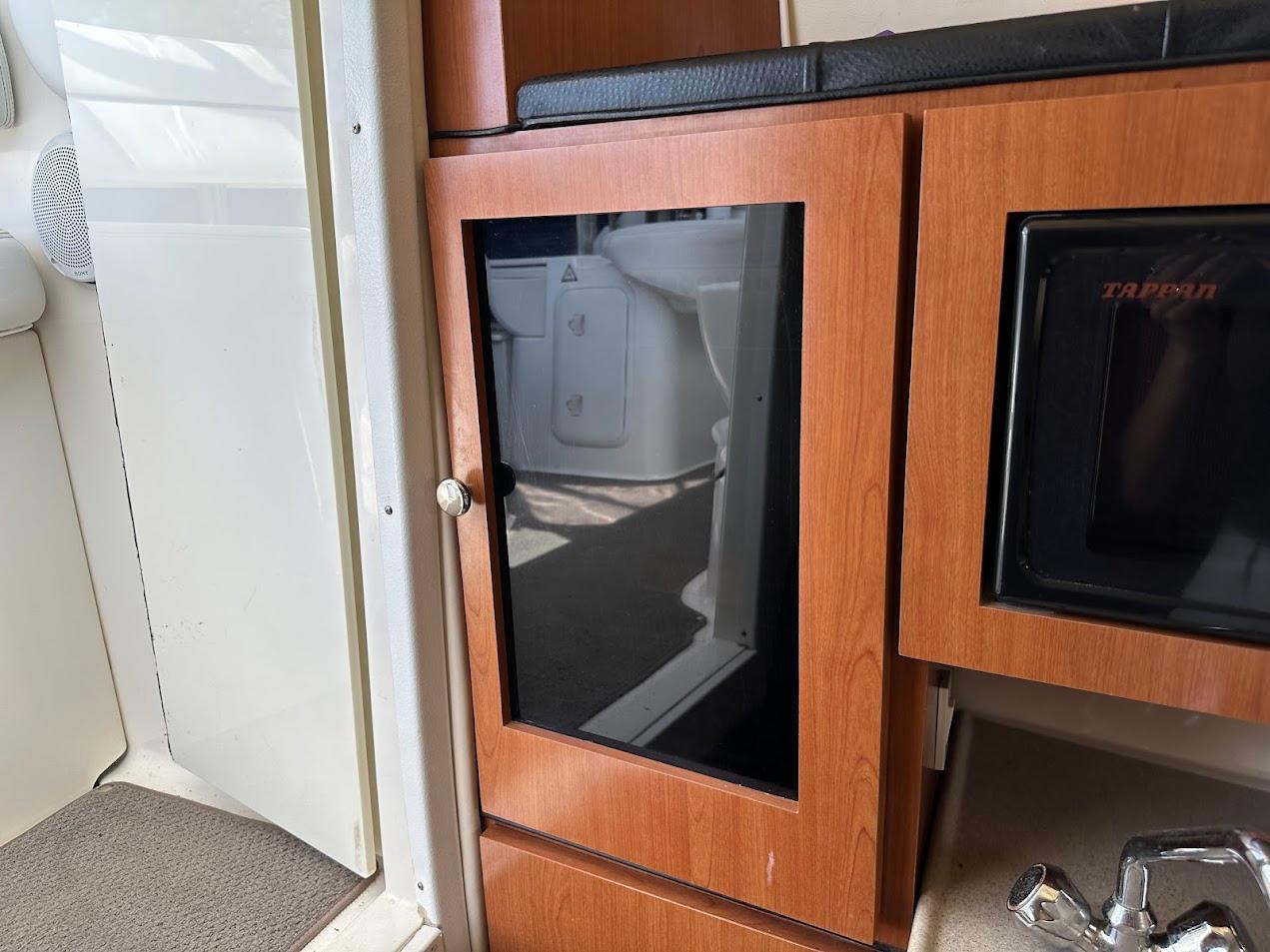 2006 Wellcraft 290 Coastal interior with wooden cabinetry and black glass door.