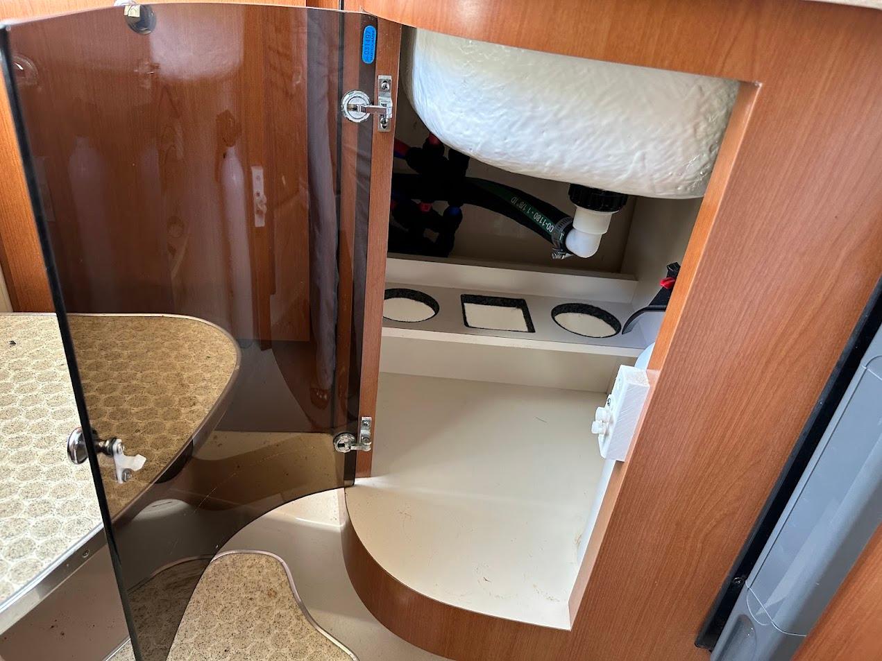 2006 Wellcraft 290 Coastal interior storage compartment with wooden finish and plumbing.