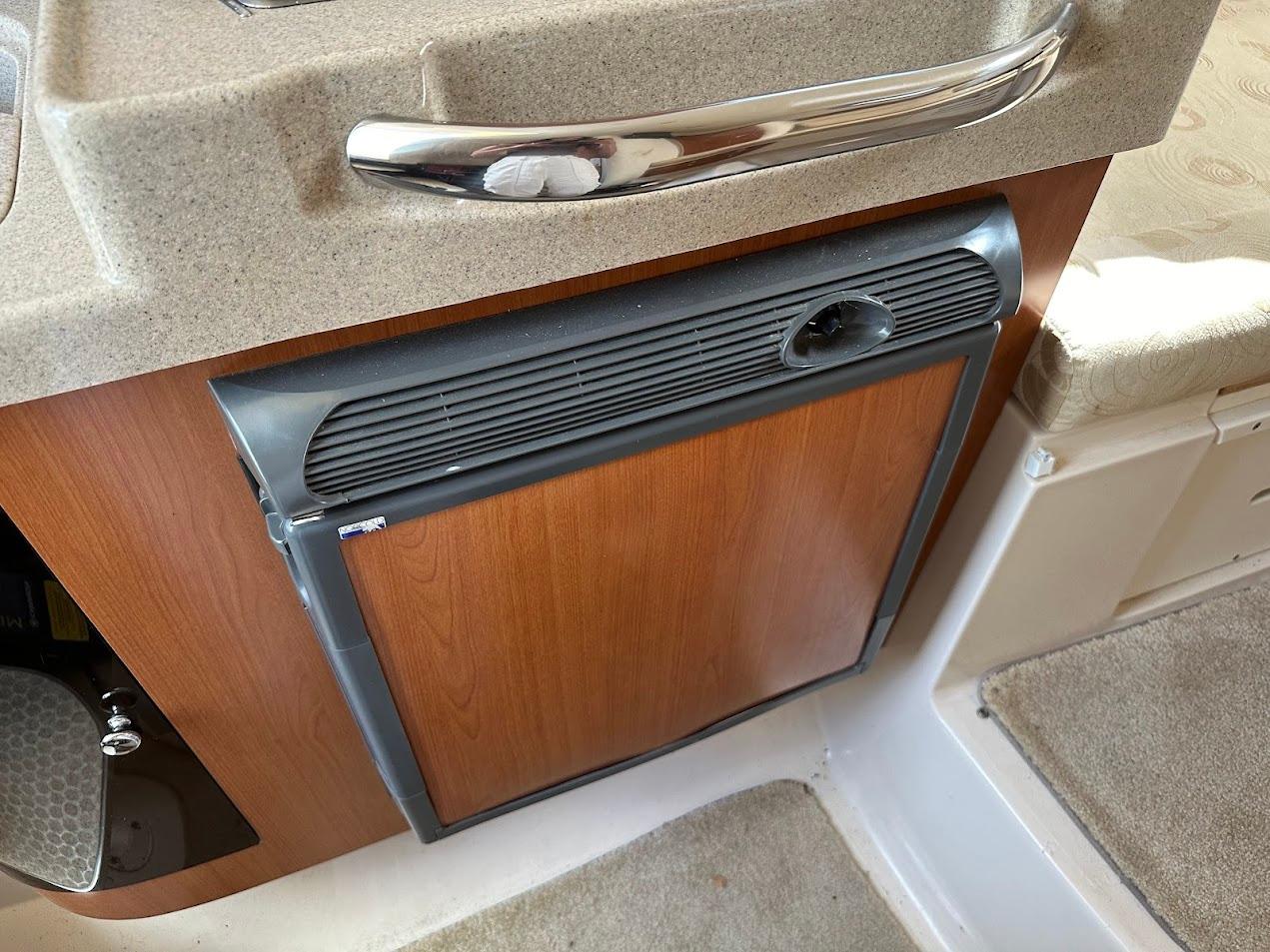 2006 Wellcraft 290 Coastal interior with compact wooden cabinet and chrome handle.