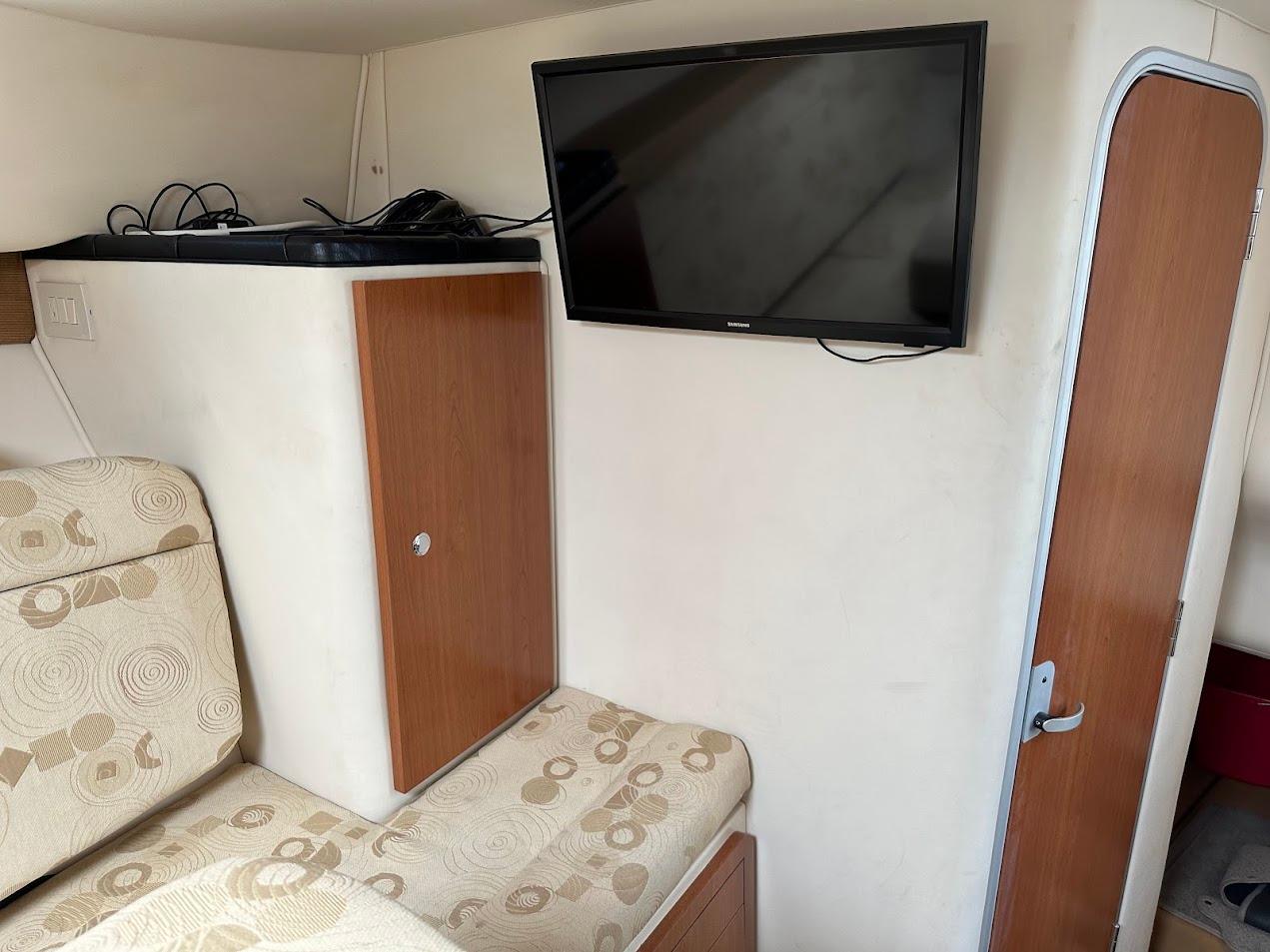 Interior of 2006 Wellcraft 290 Coastal boat with TV, seating, and wooden cabinet.