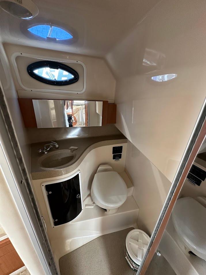2006 Wellcraft 290 Coastal boat bathroom with sink, toilet, and mirror.