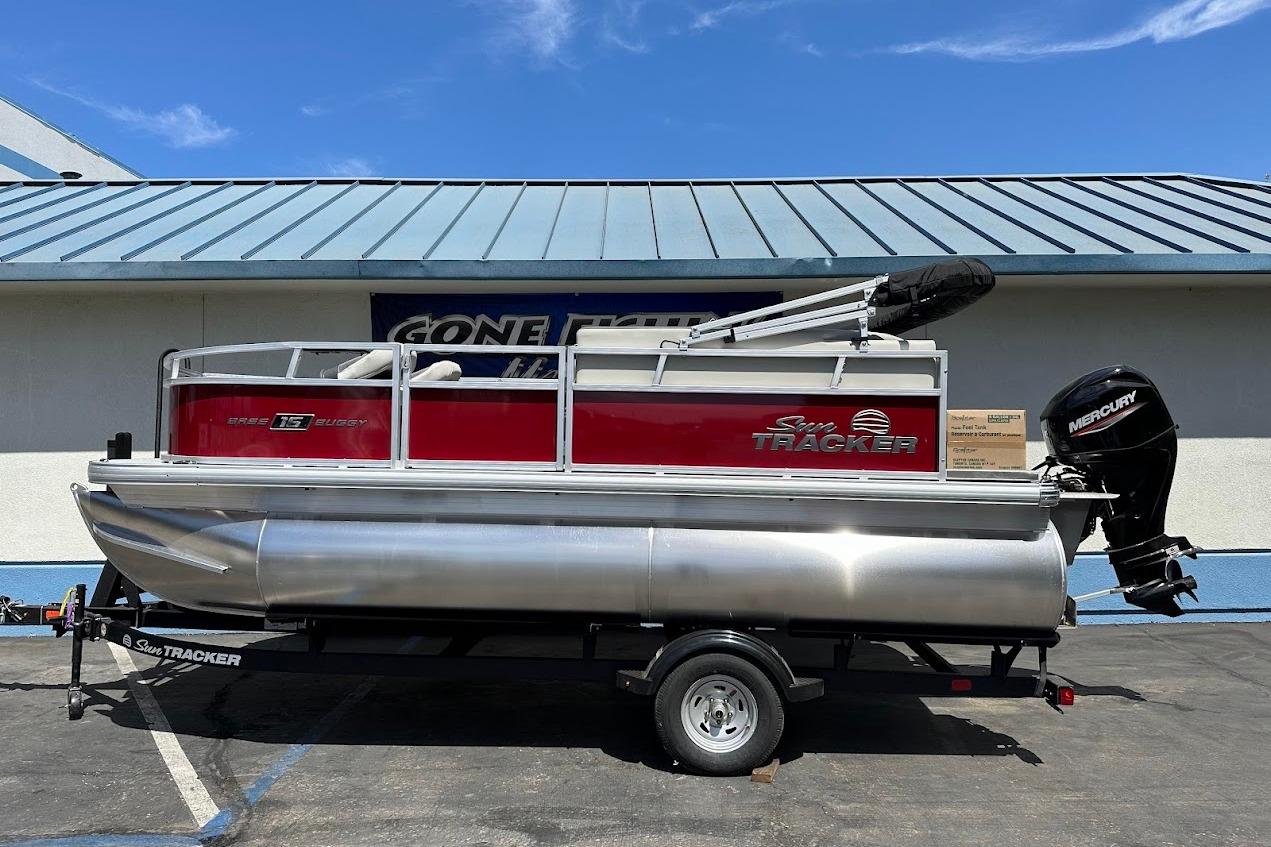 2026 Sun Tracker Bass Buggy 16 XL Select pontoon boat on trailer, parked outdoors.